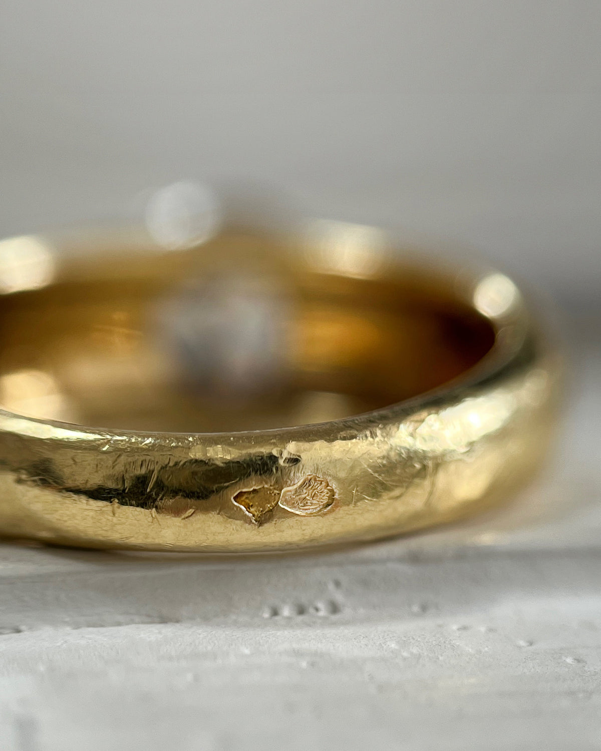 Close-up of the French eagle's head and wolf's head hallmarks on a vintage diamond solitaire ring, viewed through a jeweller's loupe.