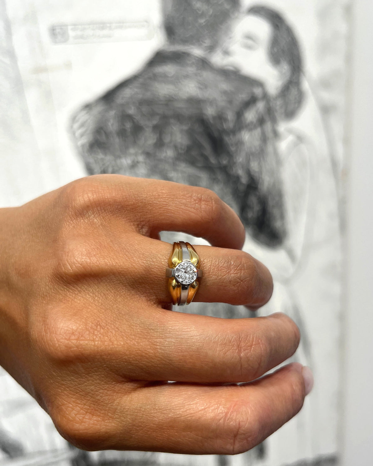 1990s vintage 18kt two-tone gold diamond solitaire engagement ring with 0.90ct Old European cut diamond in a platinum millegrain setting, held in hand against a black and white wedding photograph.