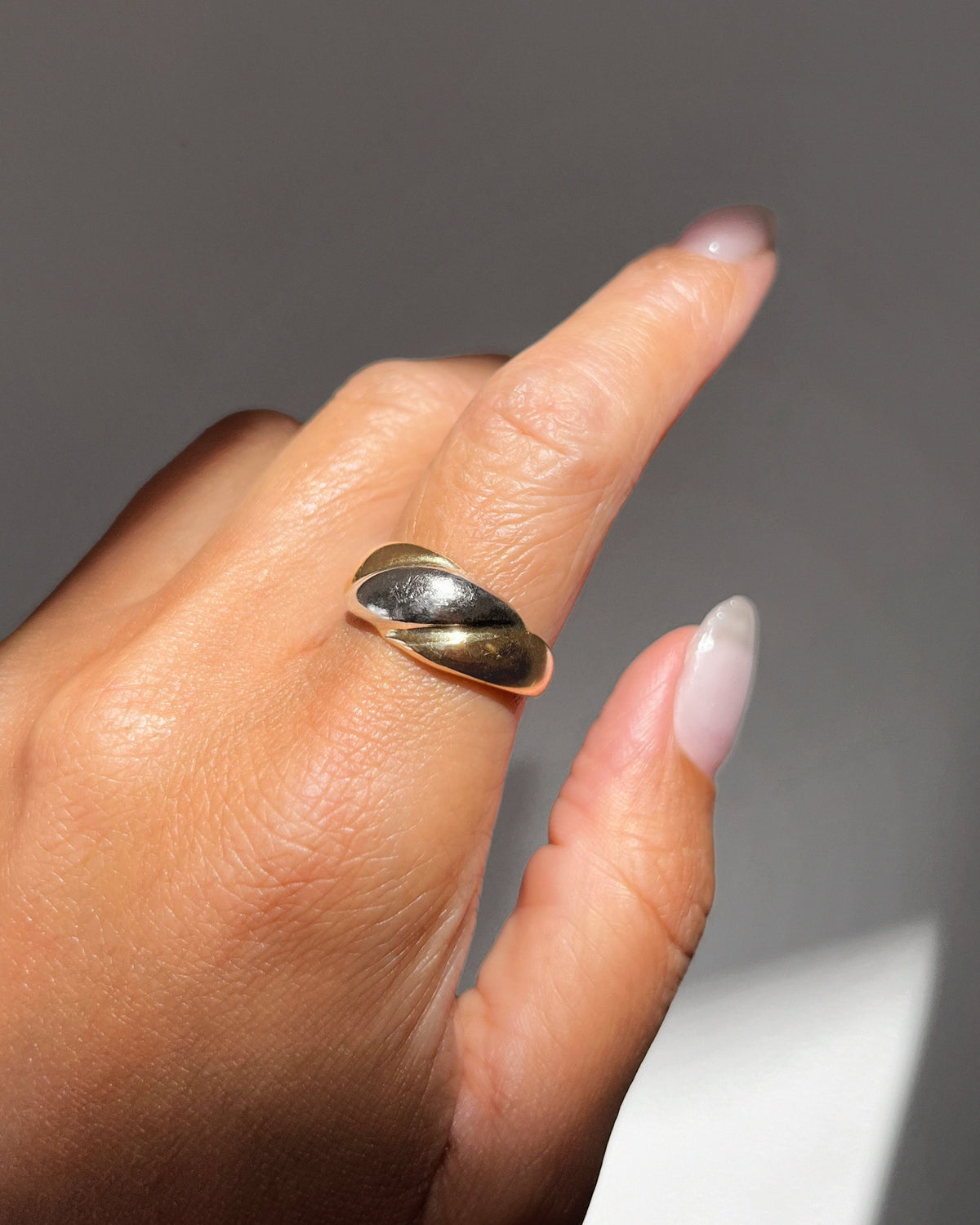 Vintage 18kt two-tone gold bombe ring with a domed white gold centre and warm yellow gold shoulders, shown on a hand.