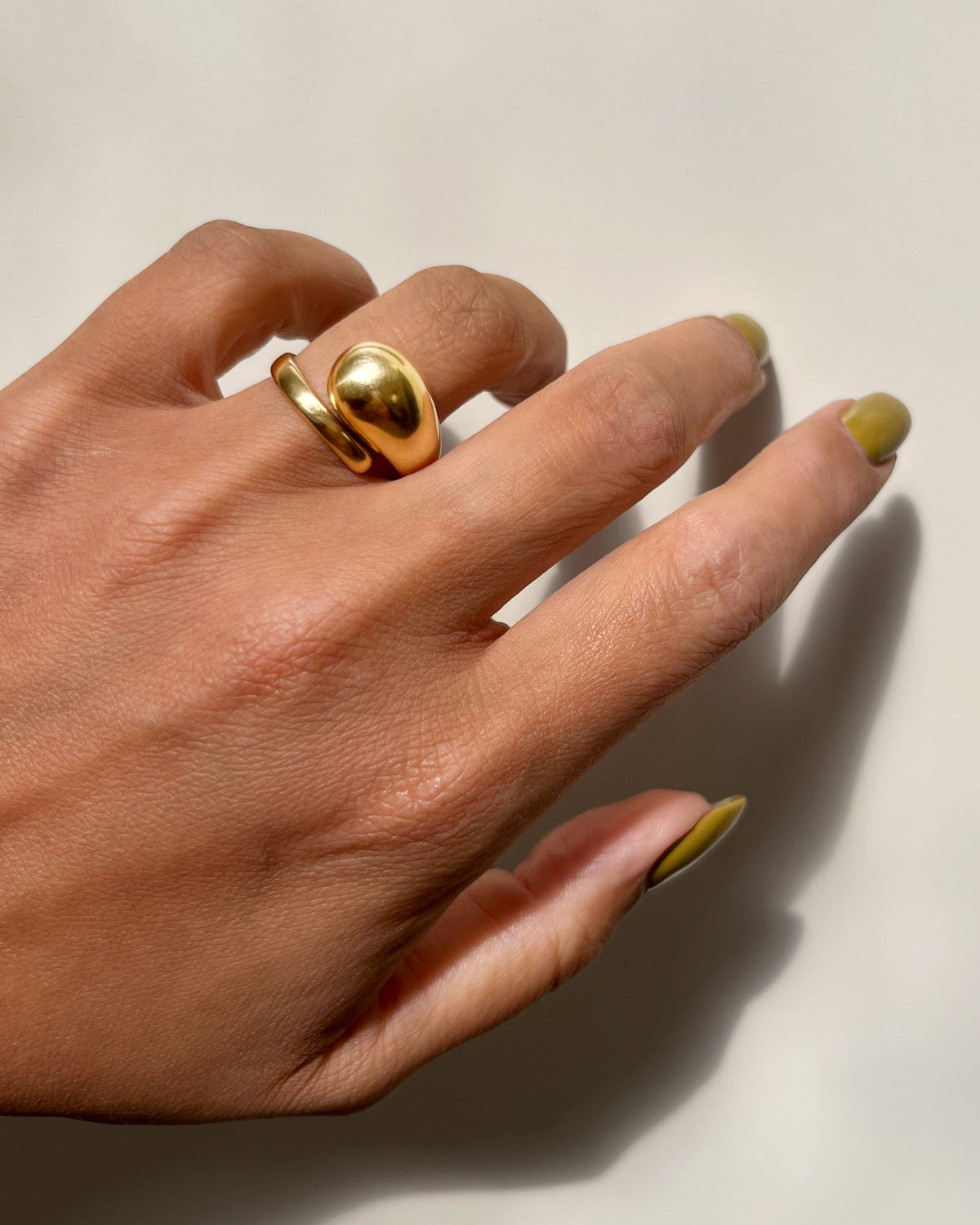 Vintage 18kt gold sculptural coil ring with an asymmetric curved band and polished bulbous domed end, shown worn on a hand against a white background.