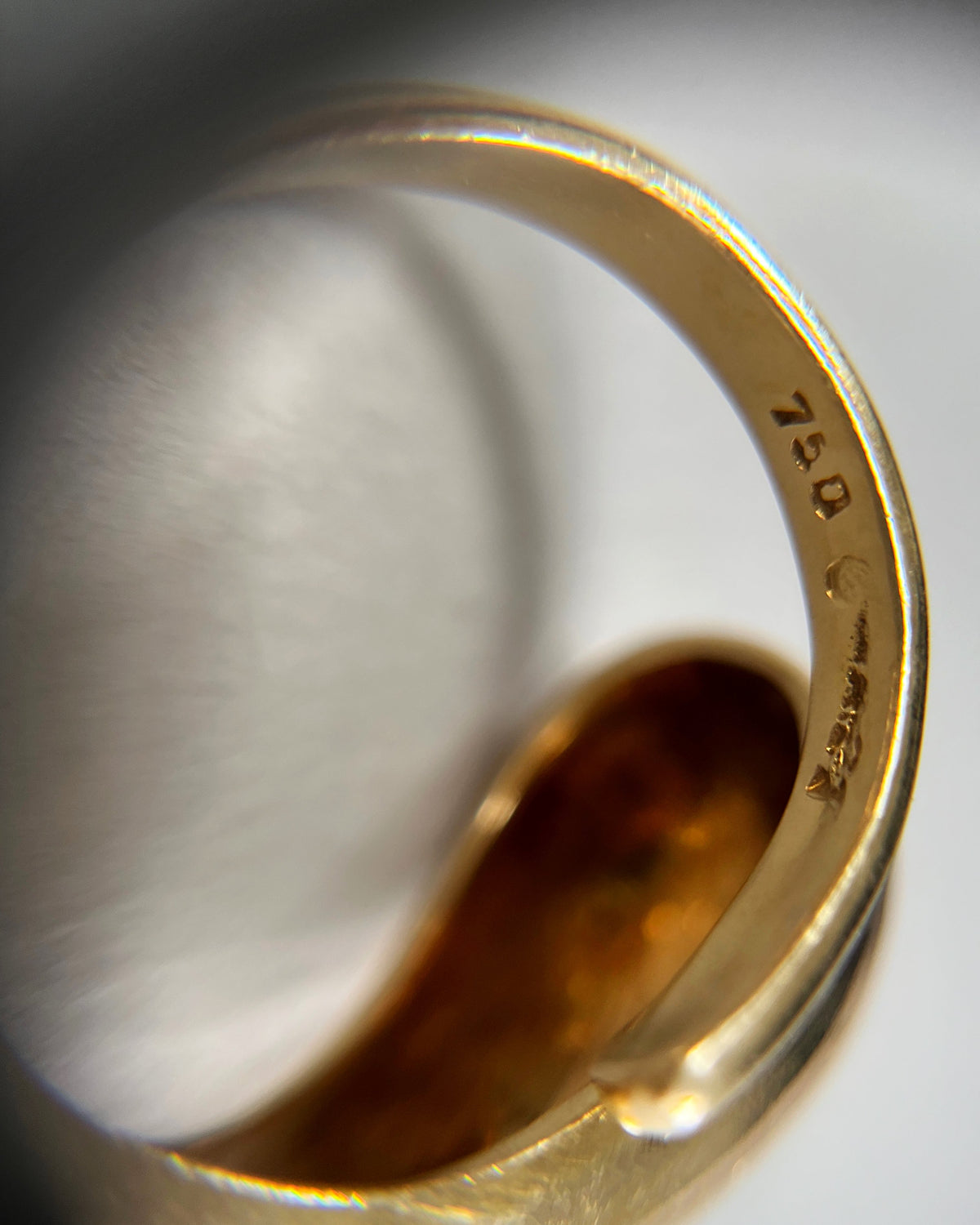 Magnified close-up of the 750 gold hallmark on a vintage 18kt gold asymmetric coil ring.