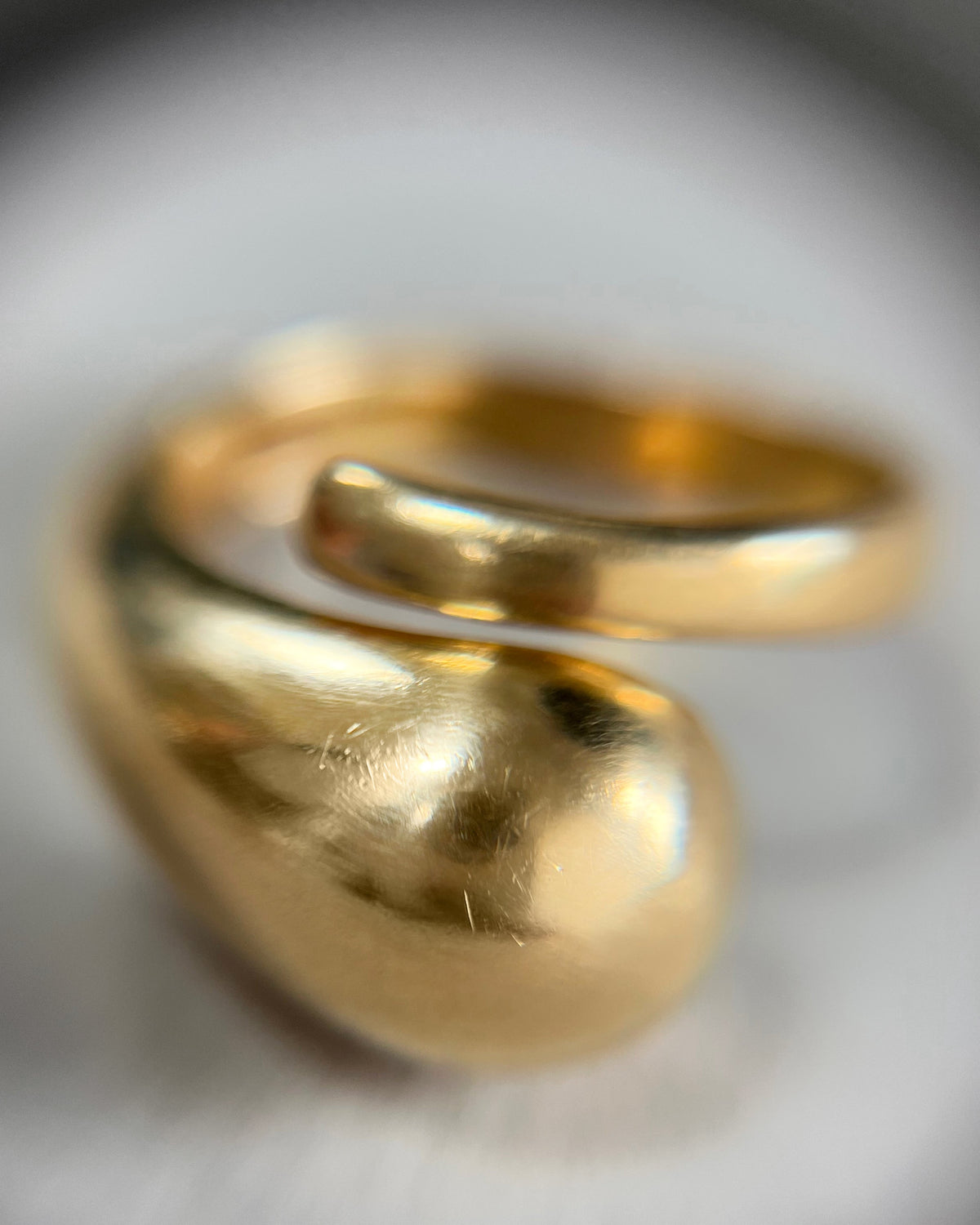 Magnified front view of a vintage 18kt gold sculptural coil ring showing the polished domed end and asymmetric design.