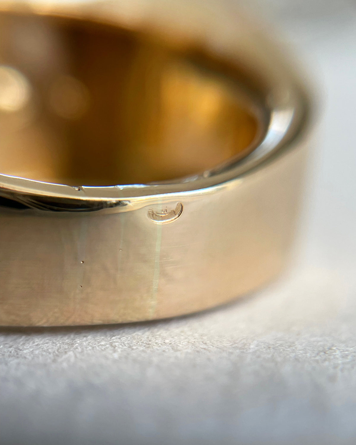 Magnified close-up of the French owl hallmark on a vintage 18kt gold tank ring, viewed through a jeweller's loupe.