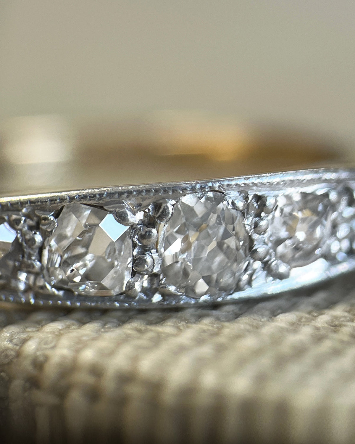 Magnified close-up of five graduating Old Mine cut diamonds with fine millegrain platinum borders on an antique five-stone diamond ring.