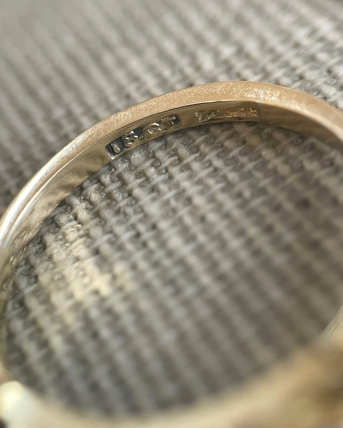Magnified close-up of the '18CT PLAT' mark inside an antique five-stone diamond ring, viewed through a jeweller's loupe.
