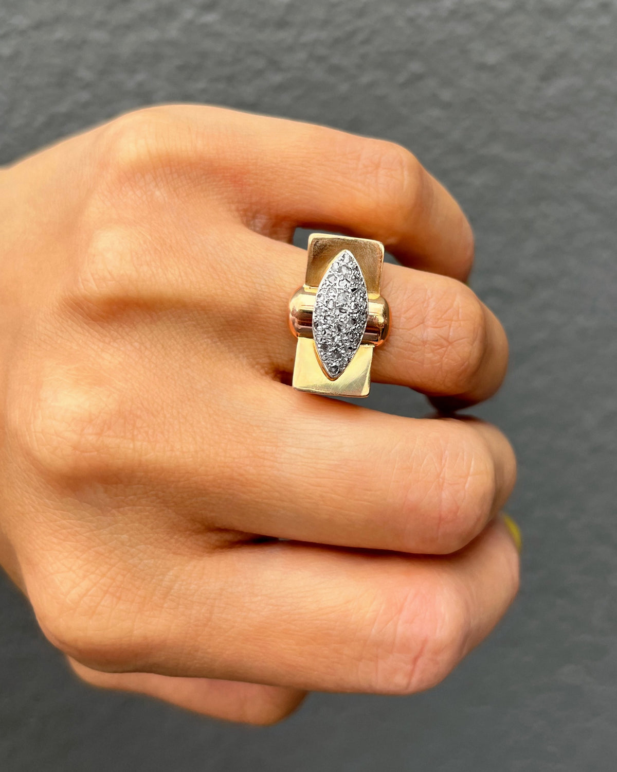 1940s vintage tank ring with rose cut diamonds in silver grain settings, shown on a hand against a grey background.