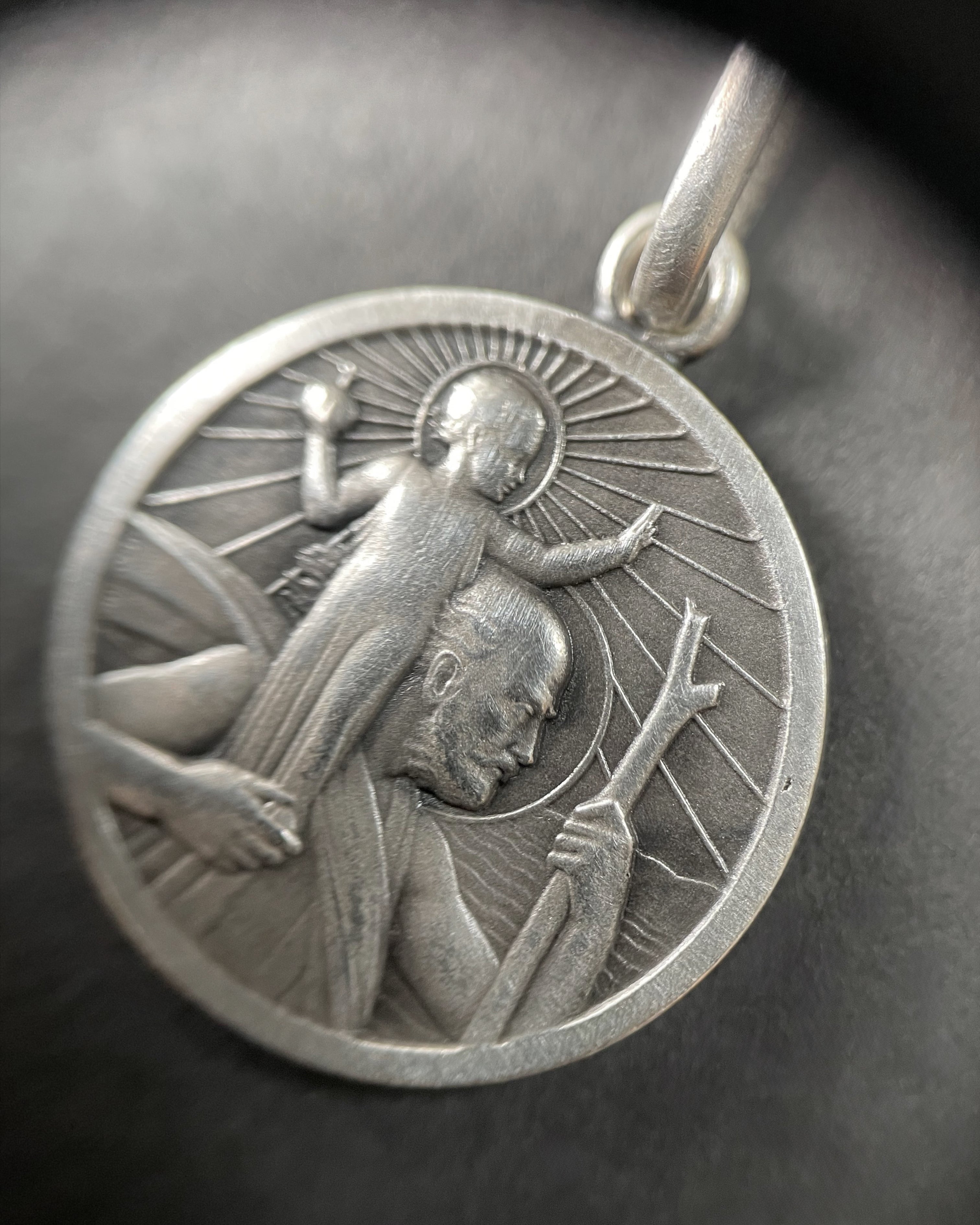 Close-up of vintage French silver St. Christopher pendant through jeweller’s loupe showing relief detail – Auric Vintage