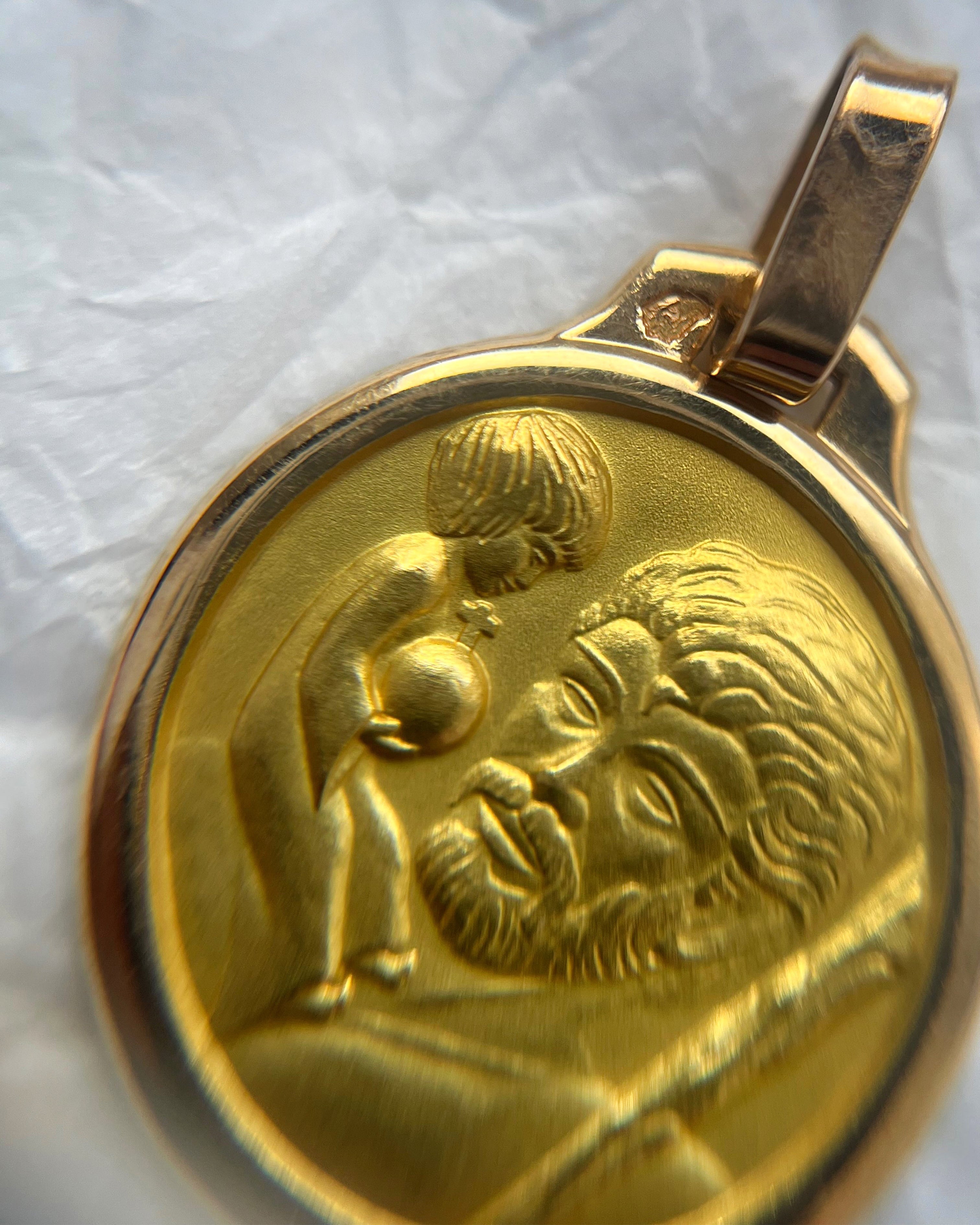Close-up of late 20th century 18kt gold St. Christopher medallion through jeweller’s loupe showing relief detail – Auric Vintage
