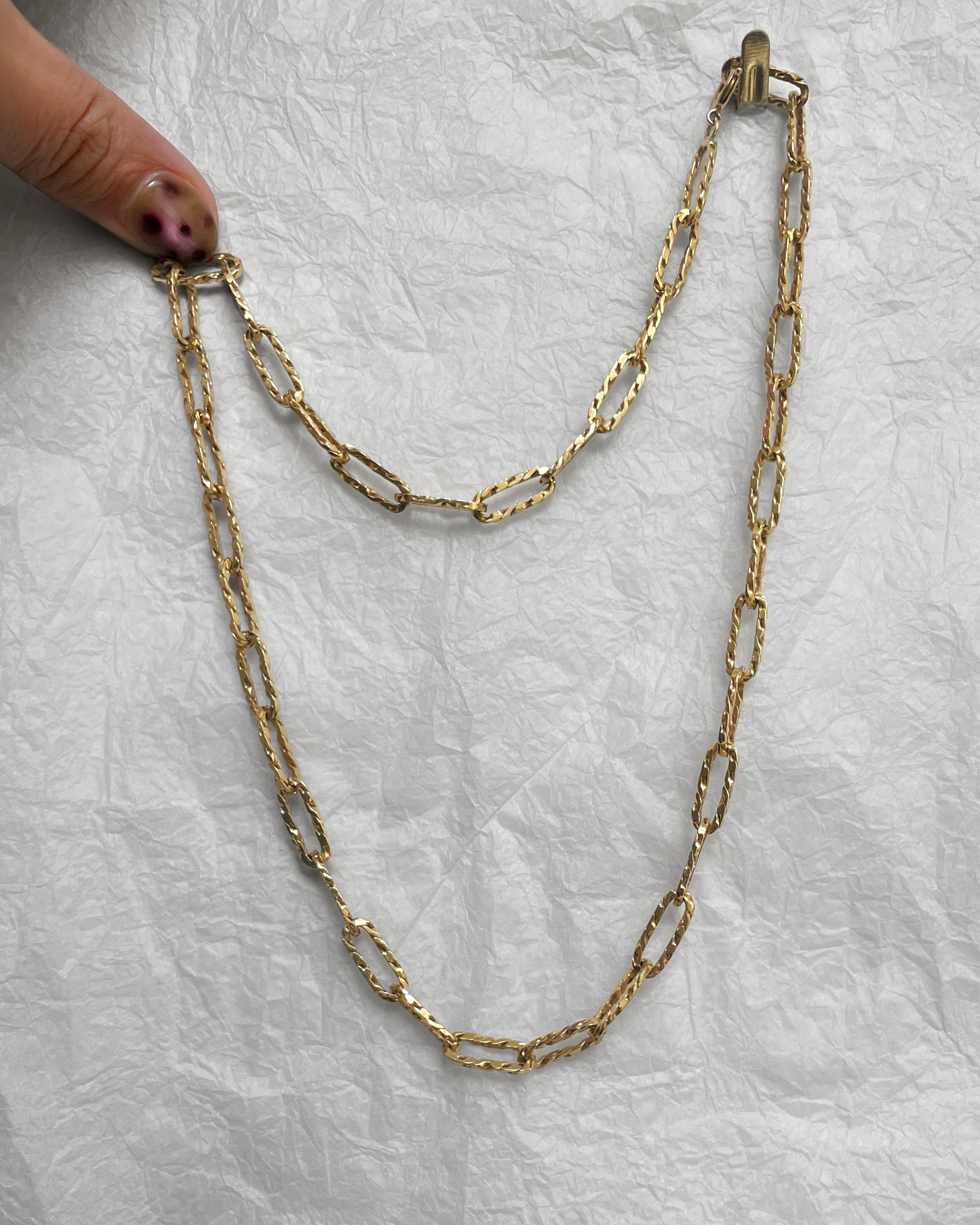 1970s textured paperlink chain in 9kt yellow gold held on finger showing elongated links and rope twist detail – Auric Vintage