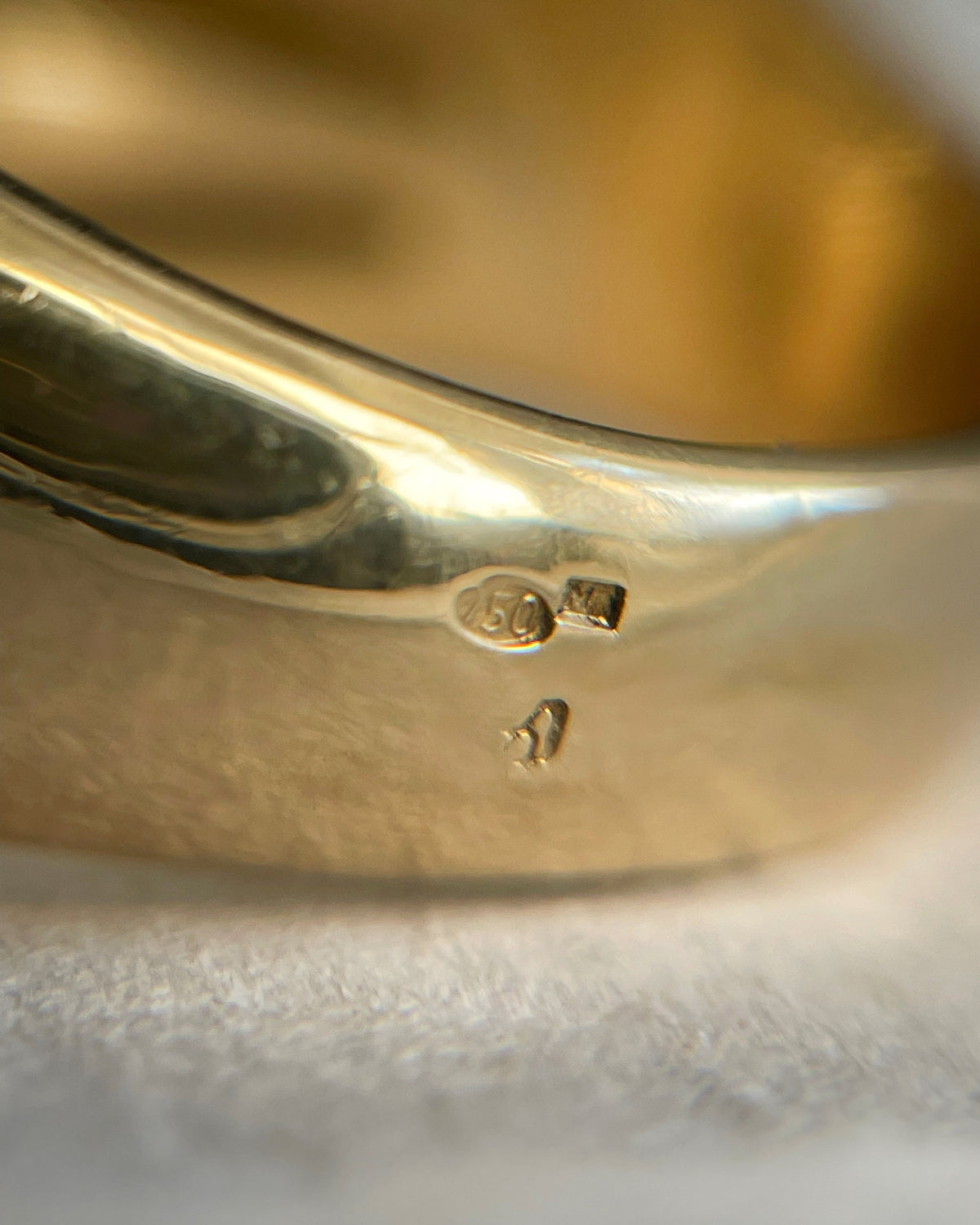 Close-up of the 750 gold hallmark on a vintage 18kt gold citrine statement ring, viewed through a jeweller's loupe.