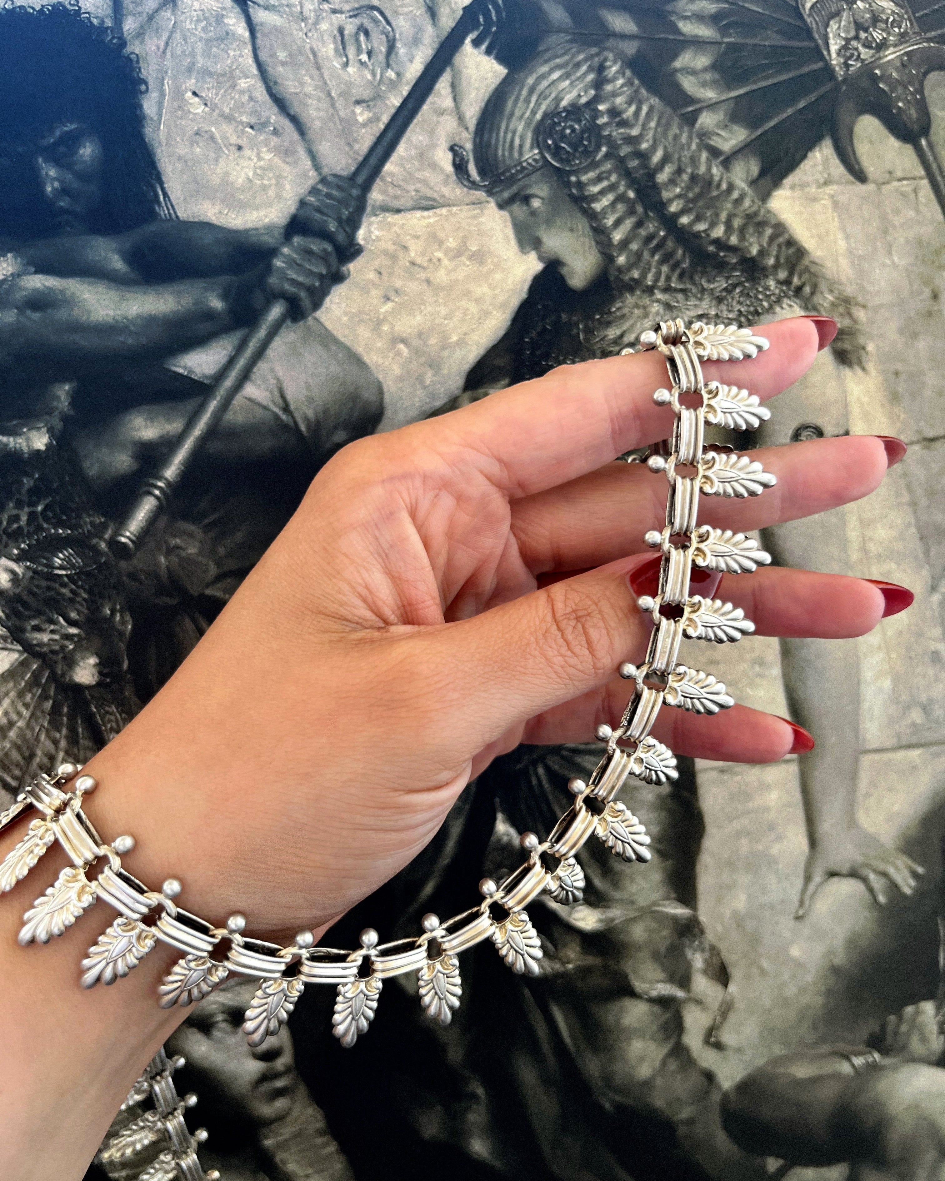 Antique Sterling silver Cleopatra palm leaf collar necklace held in hand before Egyptian artwork – Auric Vintage