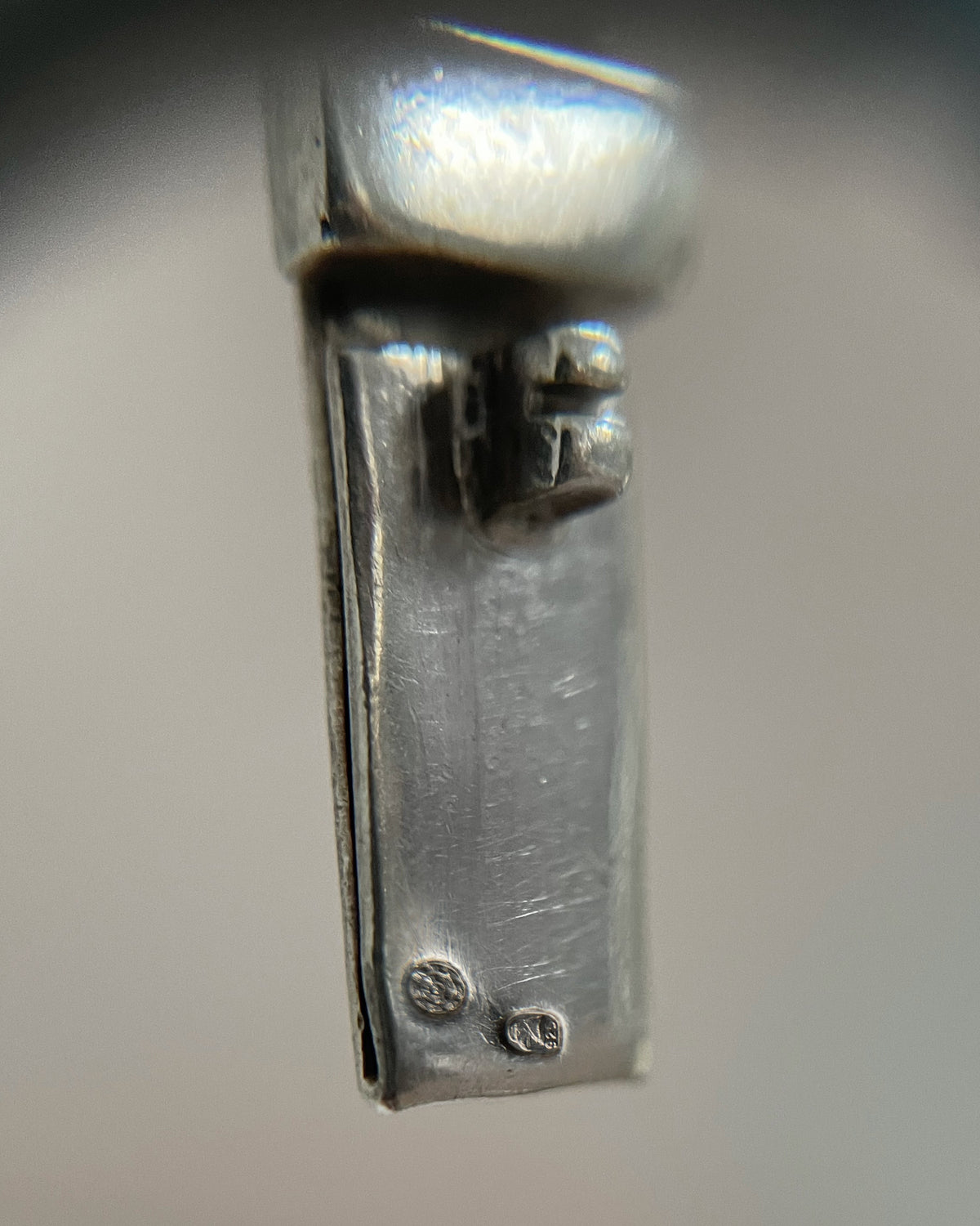 Magnified close-up of the Portuguese hawk's head and 925 Sterling silver hallmarks on a vintage Cleopatra necklace, viewed through a jeweller's loupe.