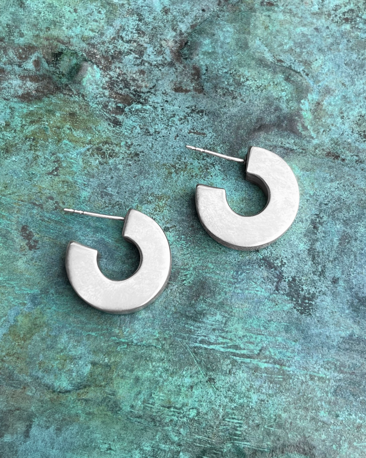 Side view of vintage Sterling silver square hoop earrings showing their chunky geometric form, polished finish and post-and-butterfly fittings.