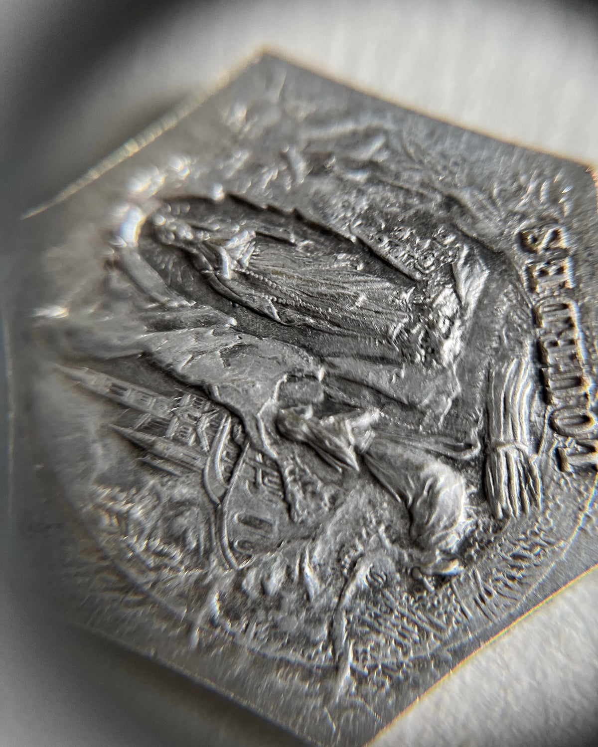 Magnified close-up of the reverse of a French St. Christopher pendant depicting the Virgin Mary appearing to Saint Bernadette at Lourdes.