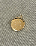 Vintage 1970s 9kt gold “I Love You” pendant with circular form and cut spiral border, shown on textured beige canvas.