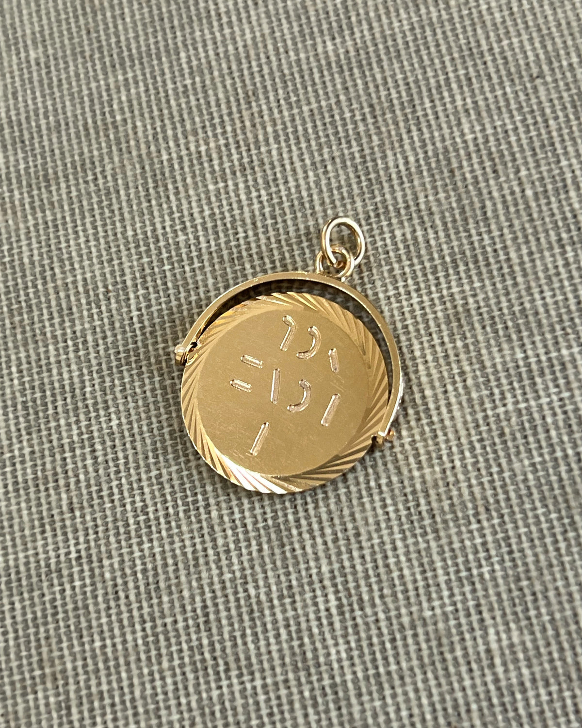 Vintage 1970s 9kt gold “I Love You” pendant with circular form and cut spiral border, shown on textured beige canvas.