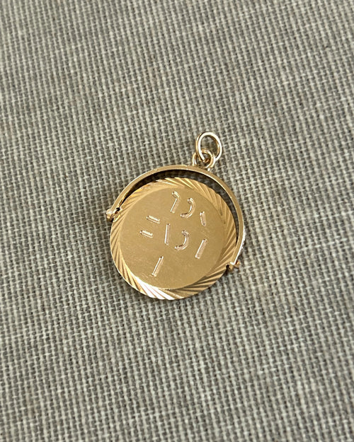 Vintage 1970s 9kt gold “I Love You” pendant with circular form and cut spiral border, shown on textured beige canvas.