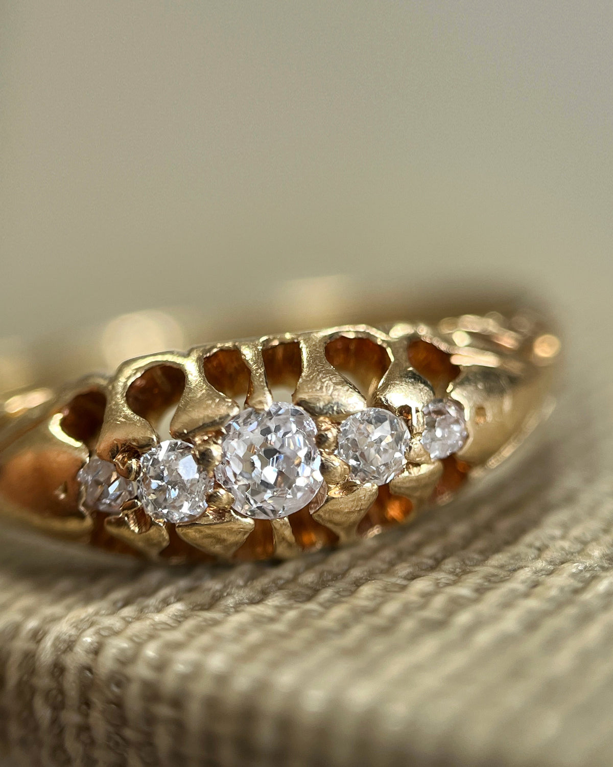 Magnified close-up of five graduating Old Mine cut diamonds in stylised claw settings on an antique five-stone diamond ring.