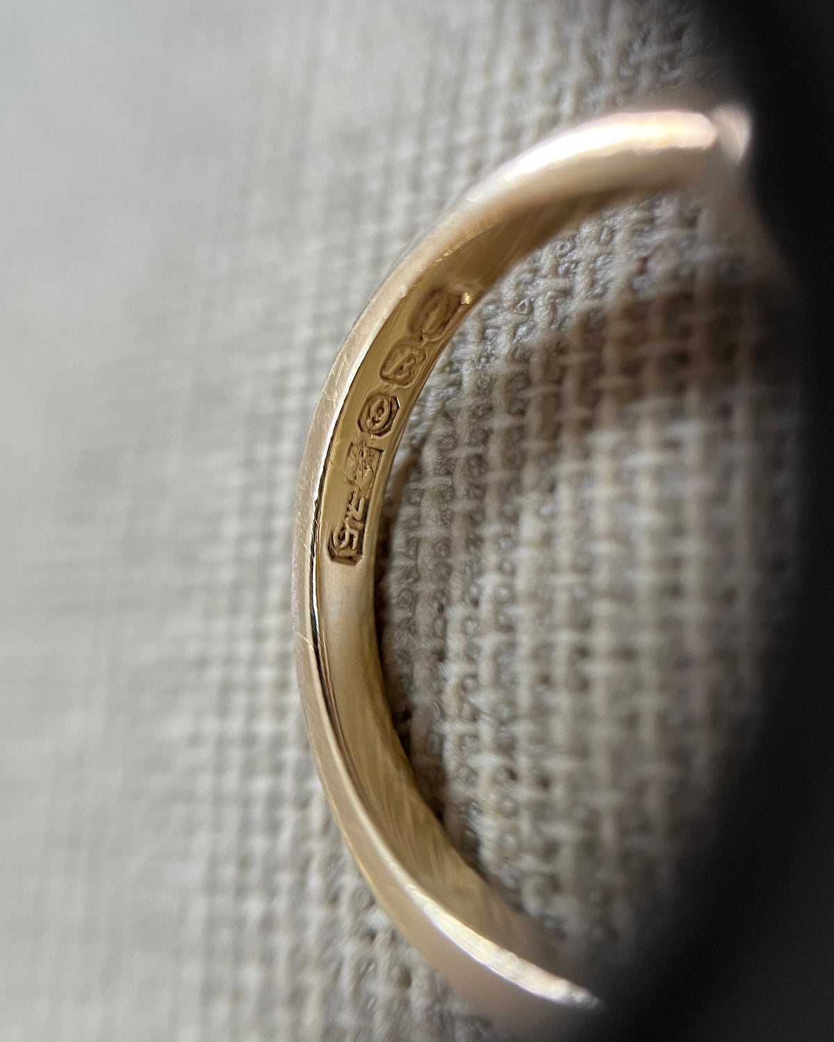 Close-up of the Hibernia Dublin hallmark, 9kt gold mark and 1990 date mark on a vintage Irish gold knot ring, viewed through a jeweller's loupe.