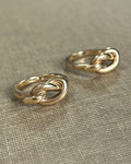 Pair of vintage Irish 9kt gold overhand knot rings shown side by side on textured beige canvas.