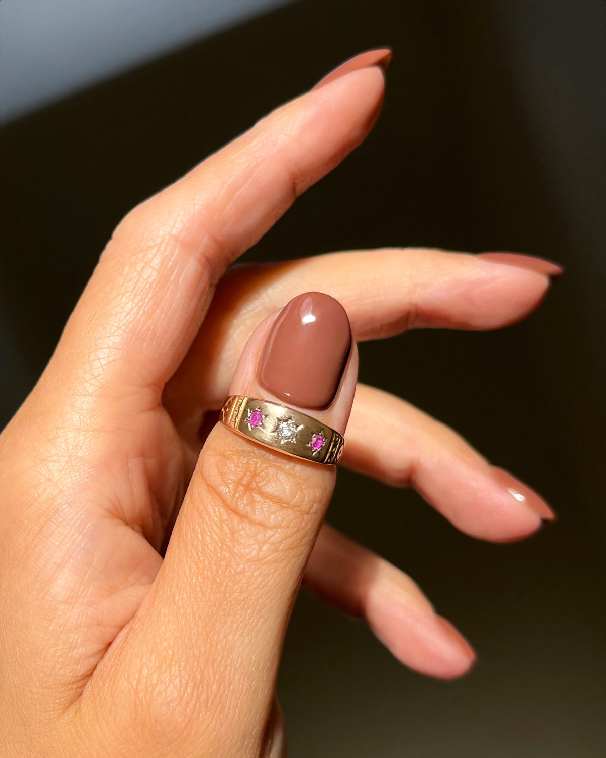 Antique 15kt gold gypsy set diamond and ruby ring shown worn on a hand, displaying the flush-set stones and decorative engraved shoulders.