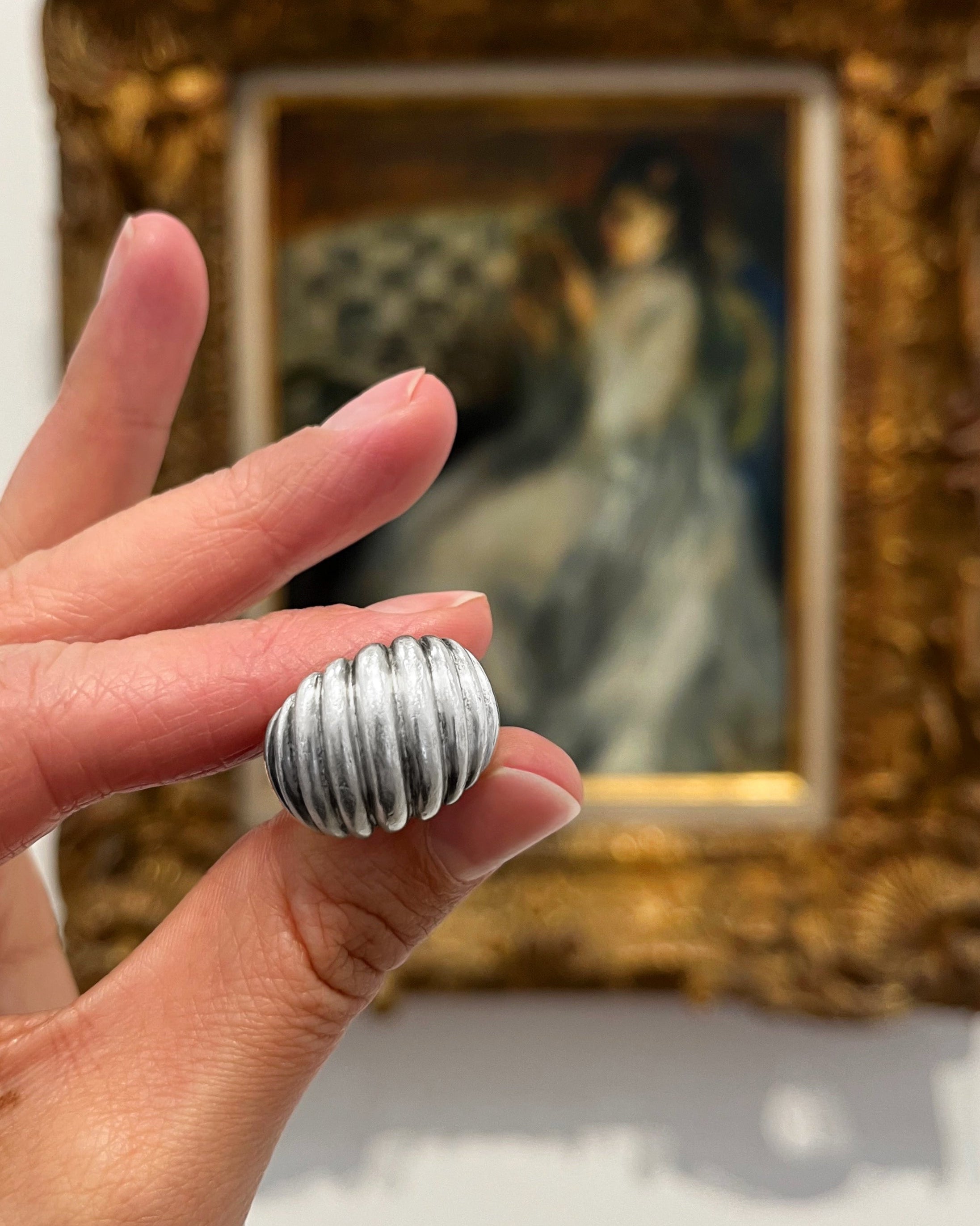 Retro sterling silver ribbed bombé ring held in hand with painting background showing sculptural form – Auric Vintage