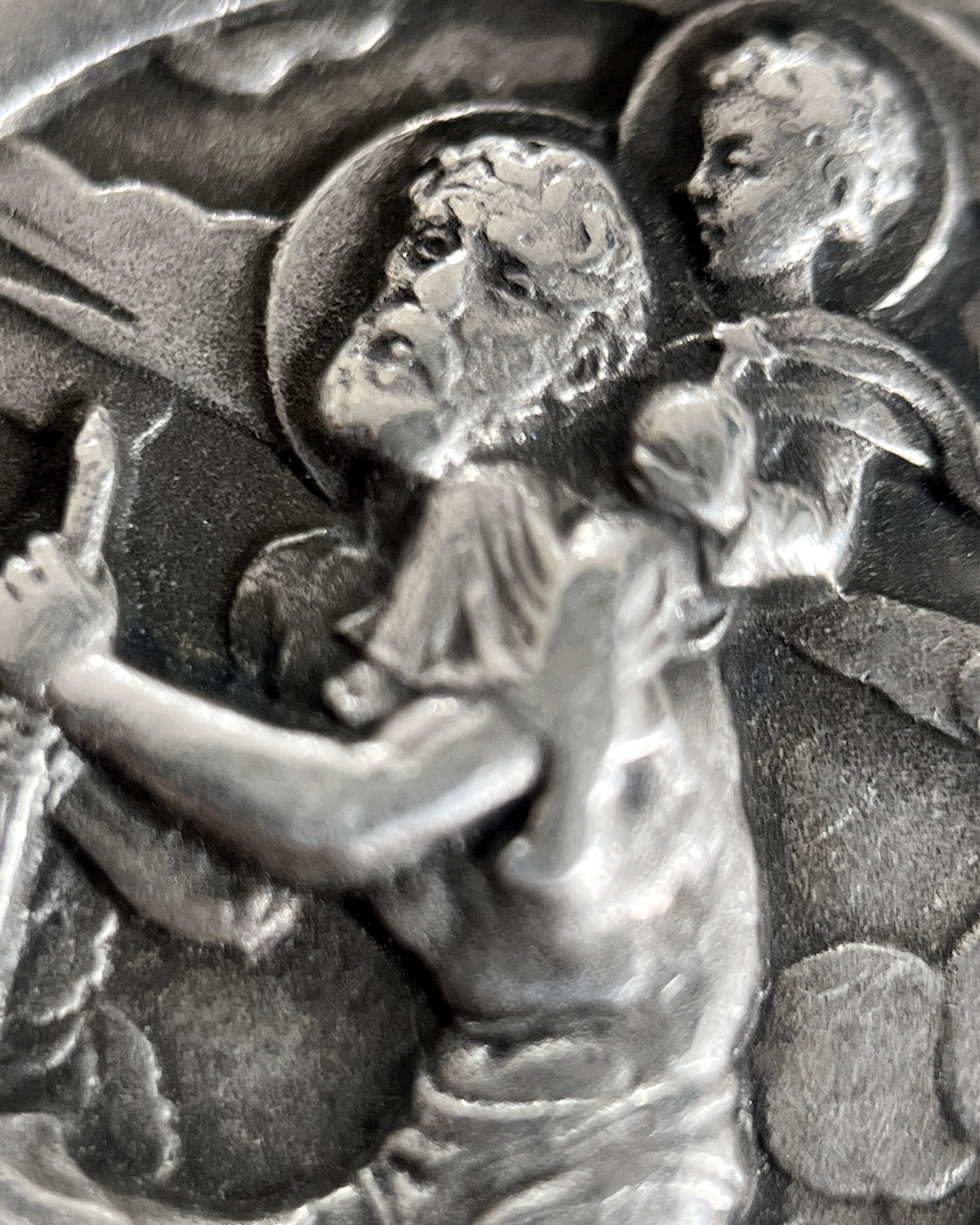 Magnified detail of 1960s French 800 silver St Christopher pendant showing St Christopher, Christ Child, turbulent waters and clouded sky