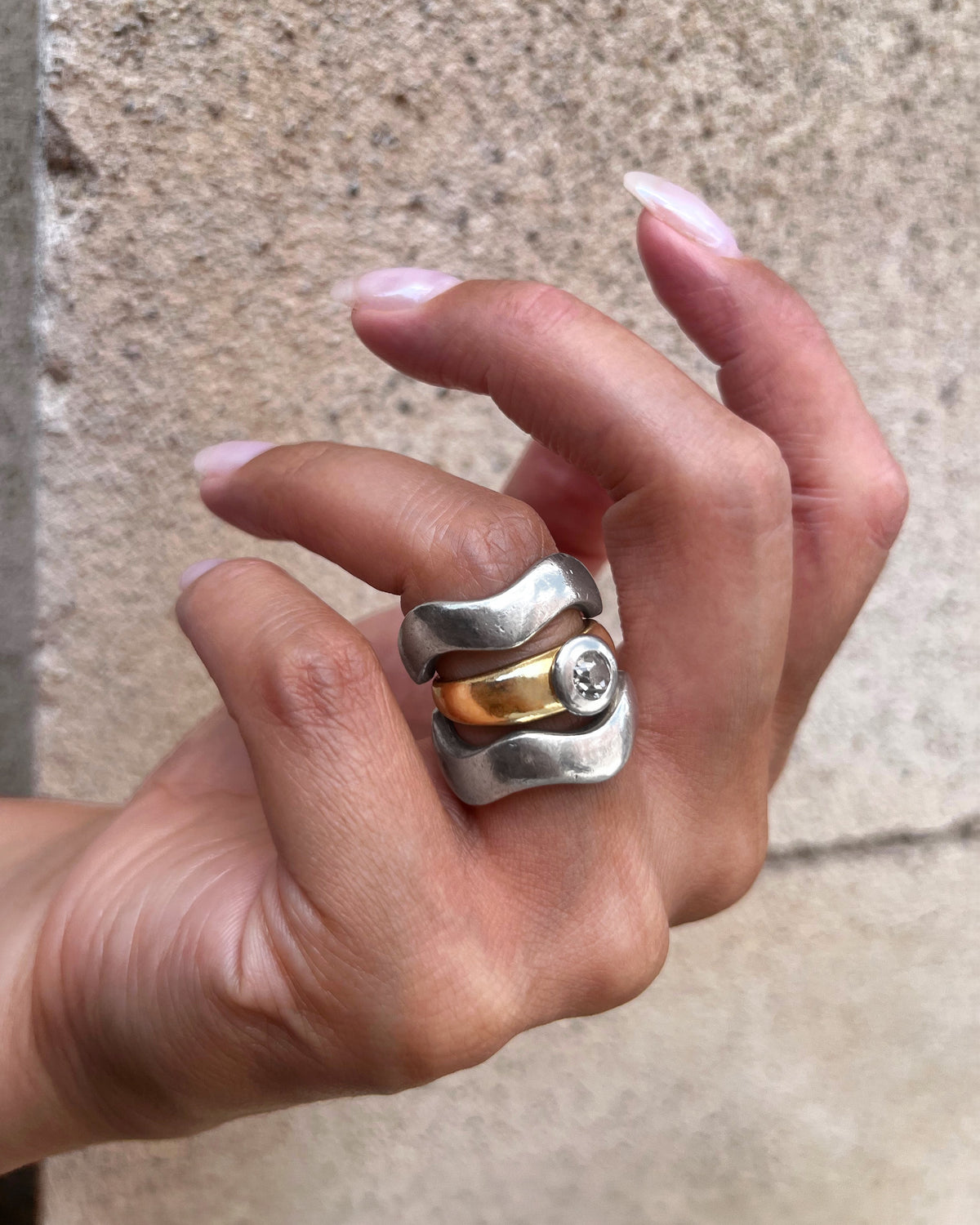 Vintage diamond solitaire engagement ring with warm Old Mine cut diamond shown on a hand, stacked with silver wave rings.