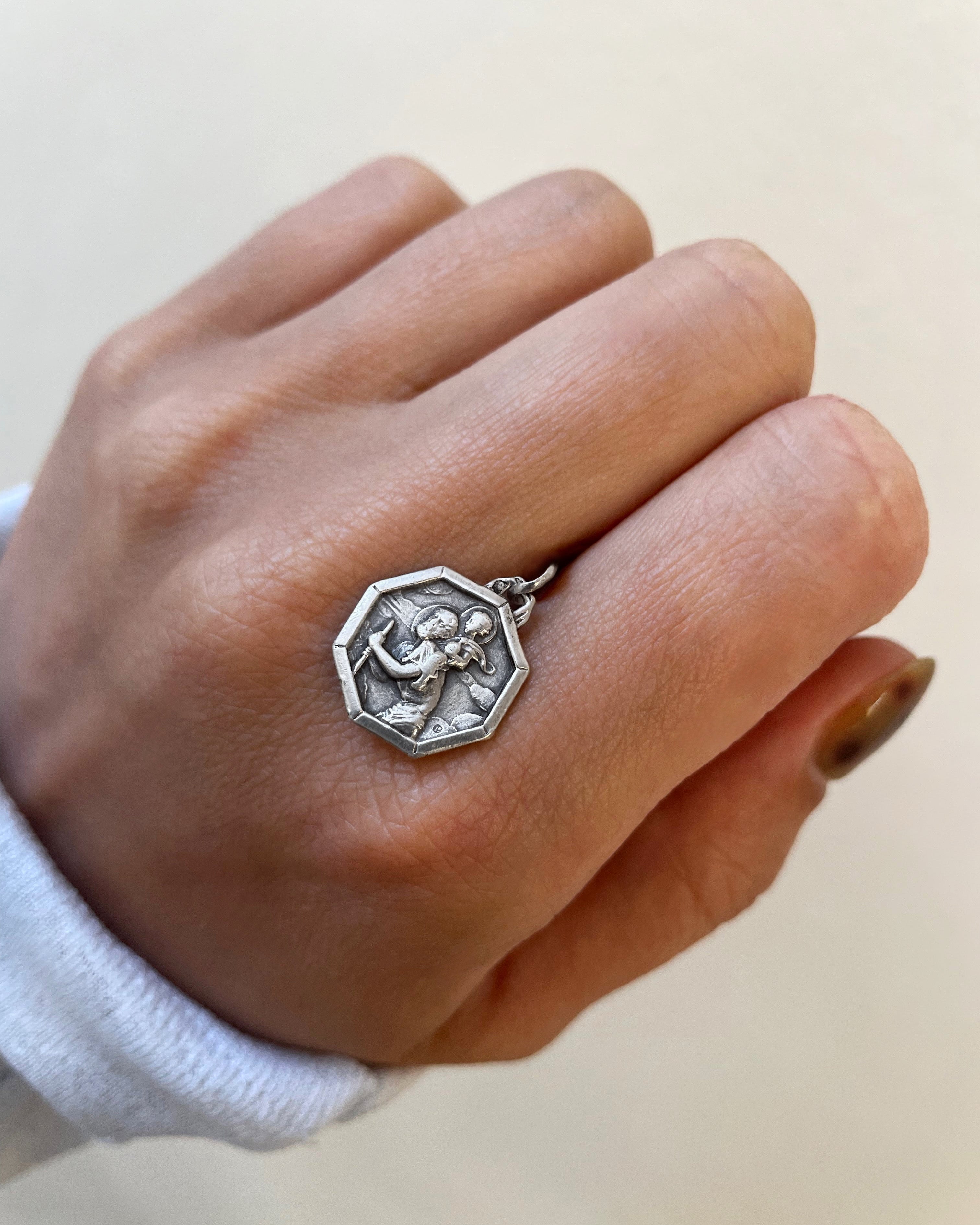 Vintage mini octagonal St. Christopher pendant in 800 silver held in hand showing scale and figural detail – Auric Vintage