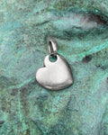 Minimalist vintage puffy heart pendant in solid Sterling silver, shown against a green bronze background.