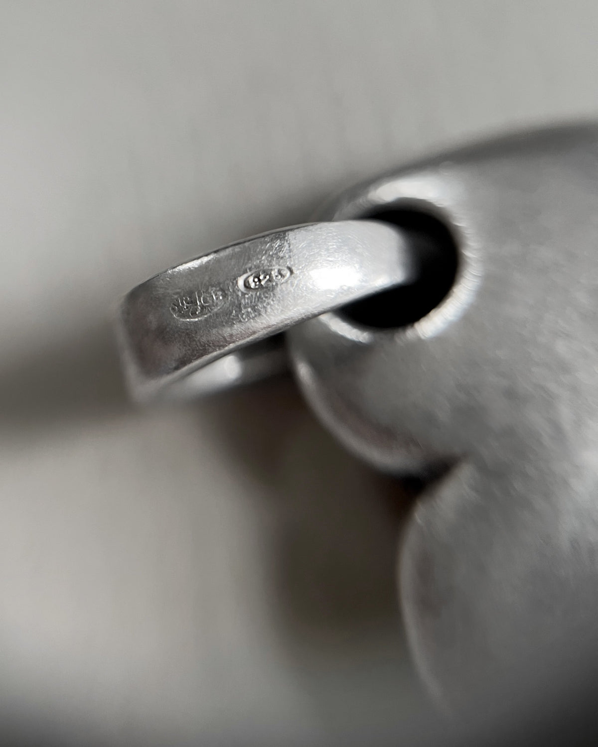 Close-up of the Sterling silver hallmark and maker's mark on a vintage puffy heart pendant, showing the engraved marks in detail.