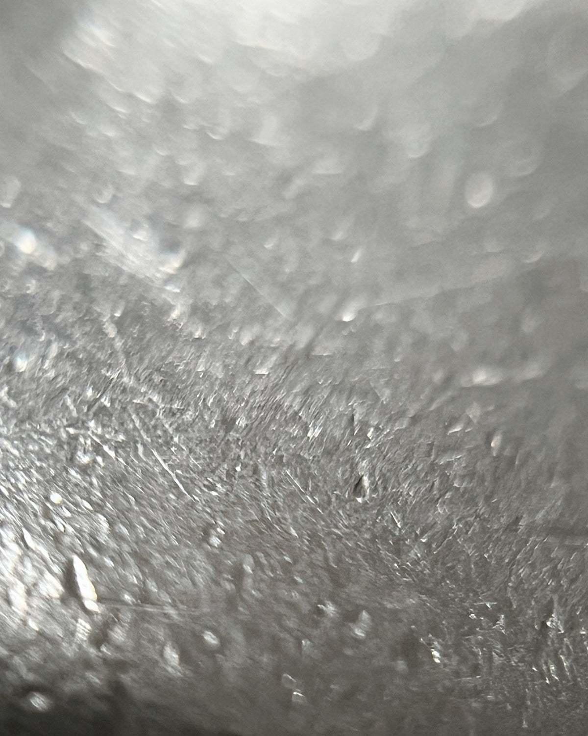 Magnified close-up of the polished surface and sculptural form of a vintage solid Sterling silver puffy heart pendant.