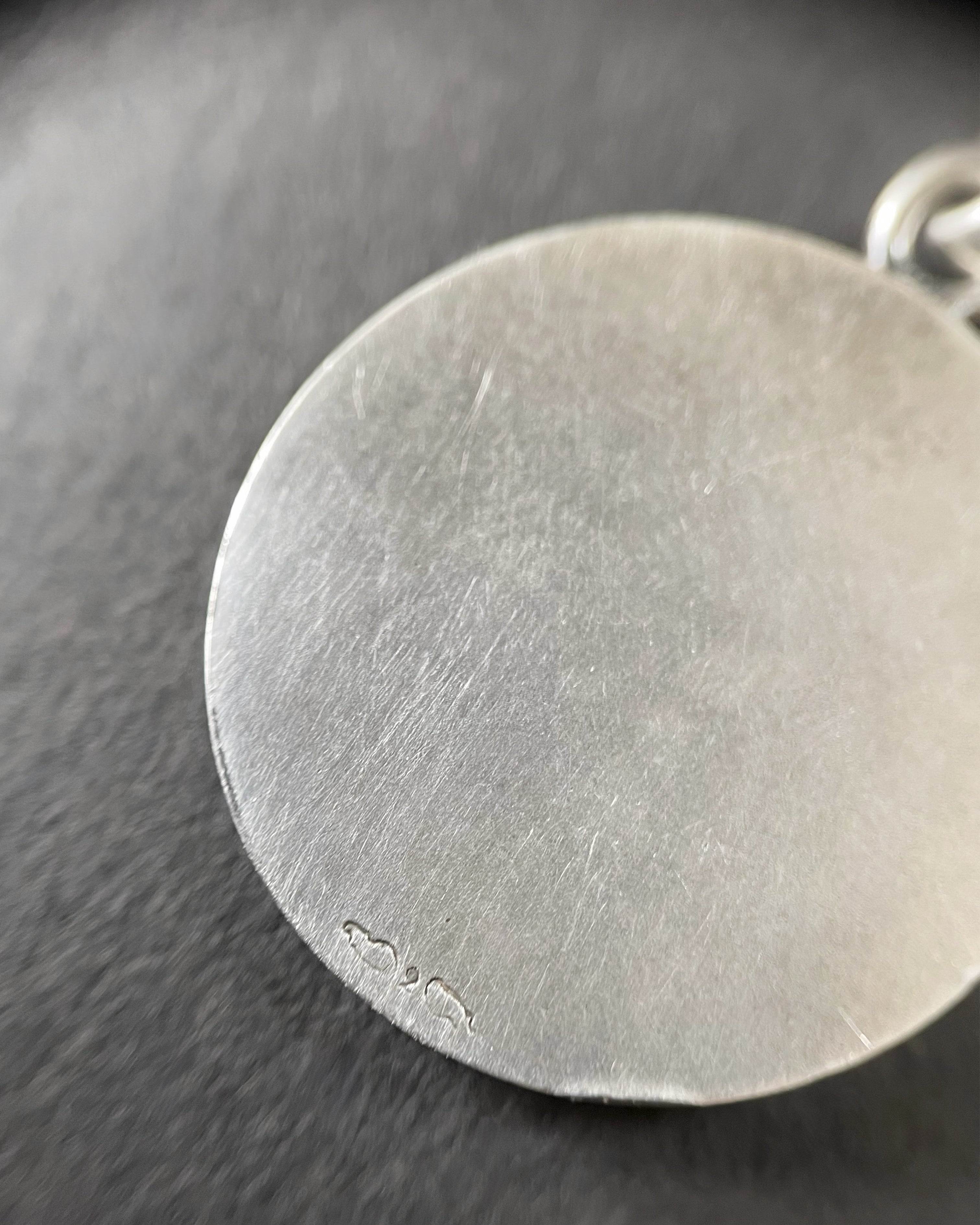 Magnified reverse of vintage French St. Christopher pendant in silver showing back detail – Auric Vintage