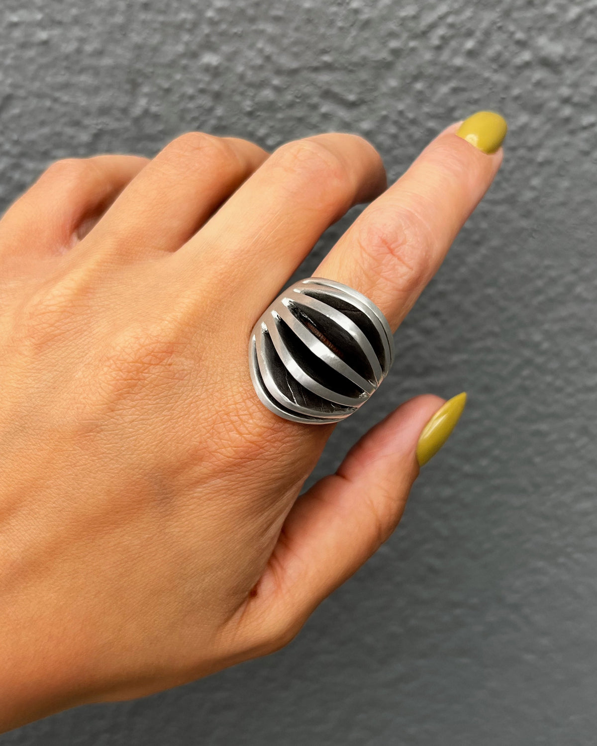 Vintage Sterling silver statement dress ring with seven graduating open ridges reaching towards the centre, shown on a hand.