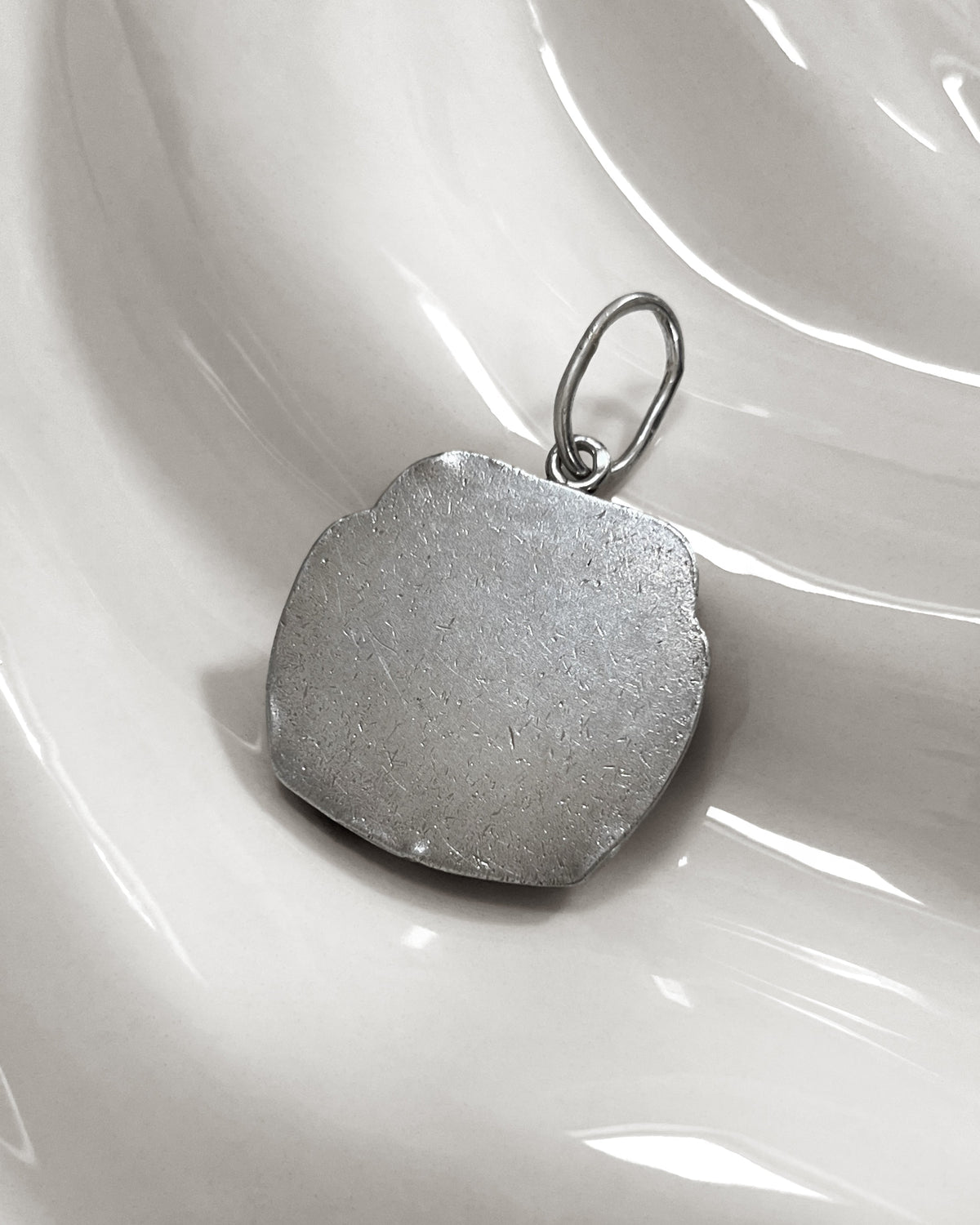 Reverse of 1940s French vintage sterling silver Gemini pendant showing the sculptural carved figures and pendant bale