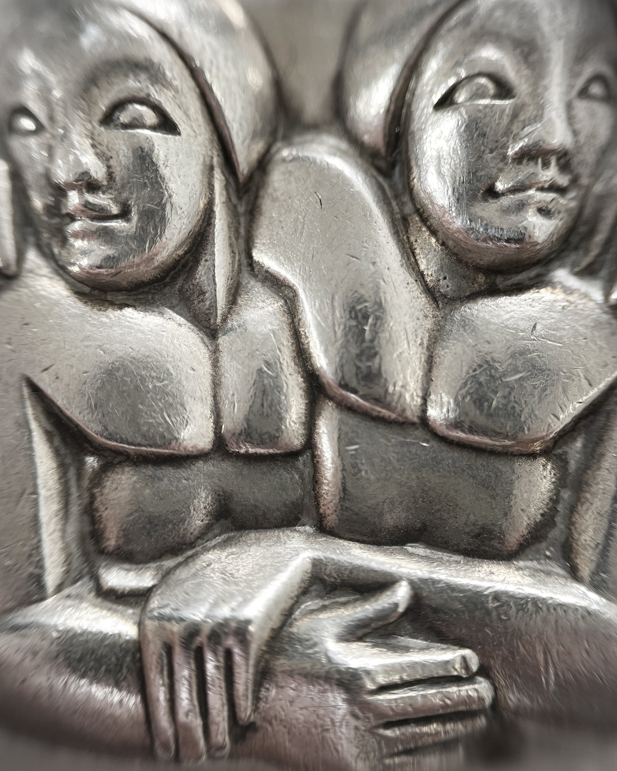Close-up of 1940s French sterling silver Gemini pendant depicting two angular entwined figures in a sculptural Art Deco style