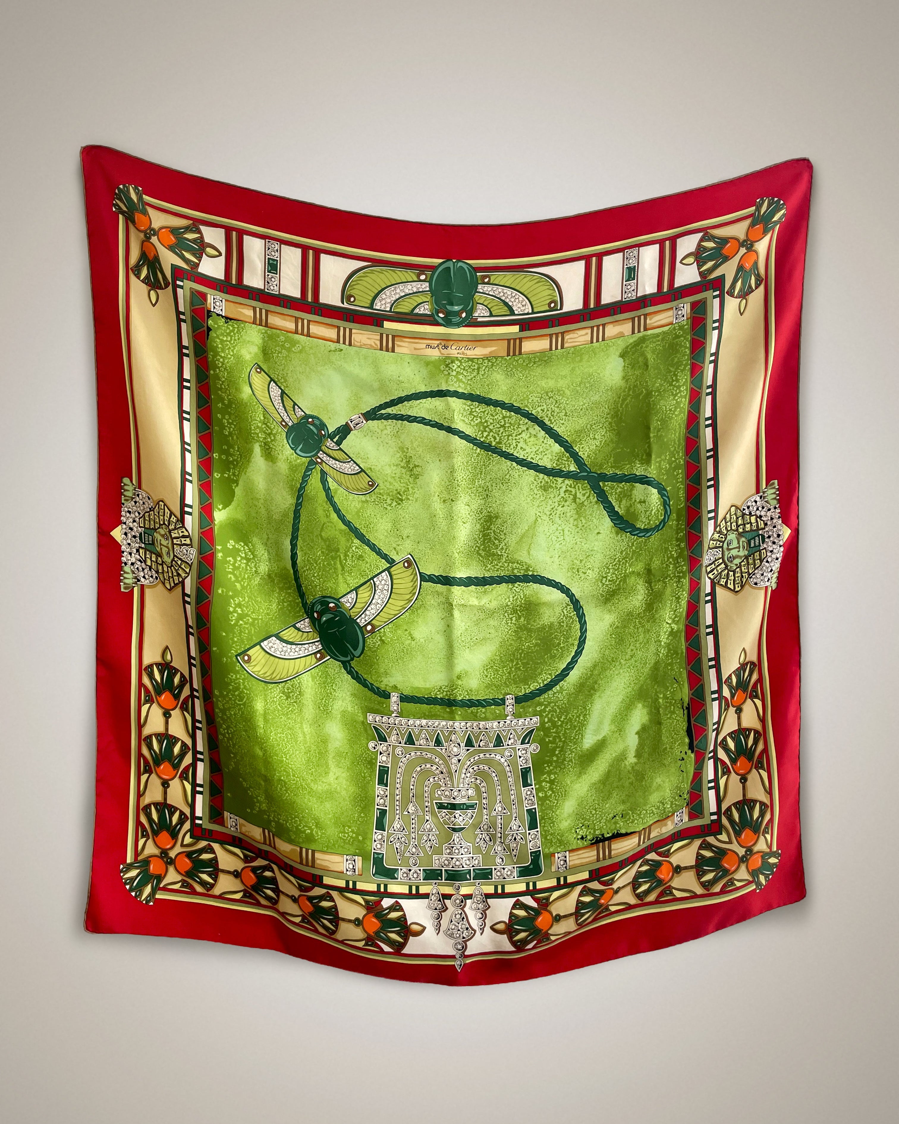 Vintage Must de Cartier Le Scarabée silk scarf in light green featuring Egyptomania-inspired design, hanging display – Auric Vintage