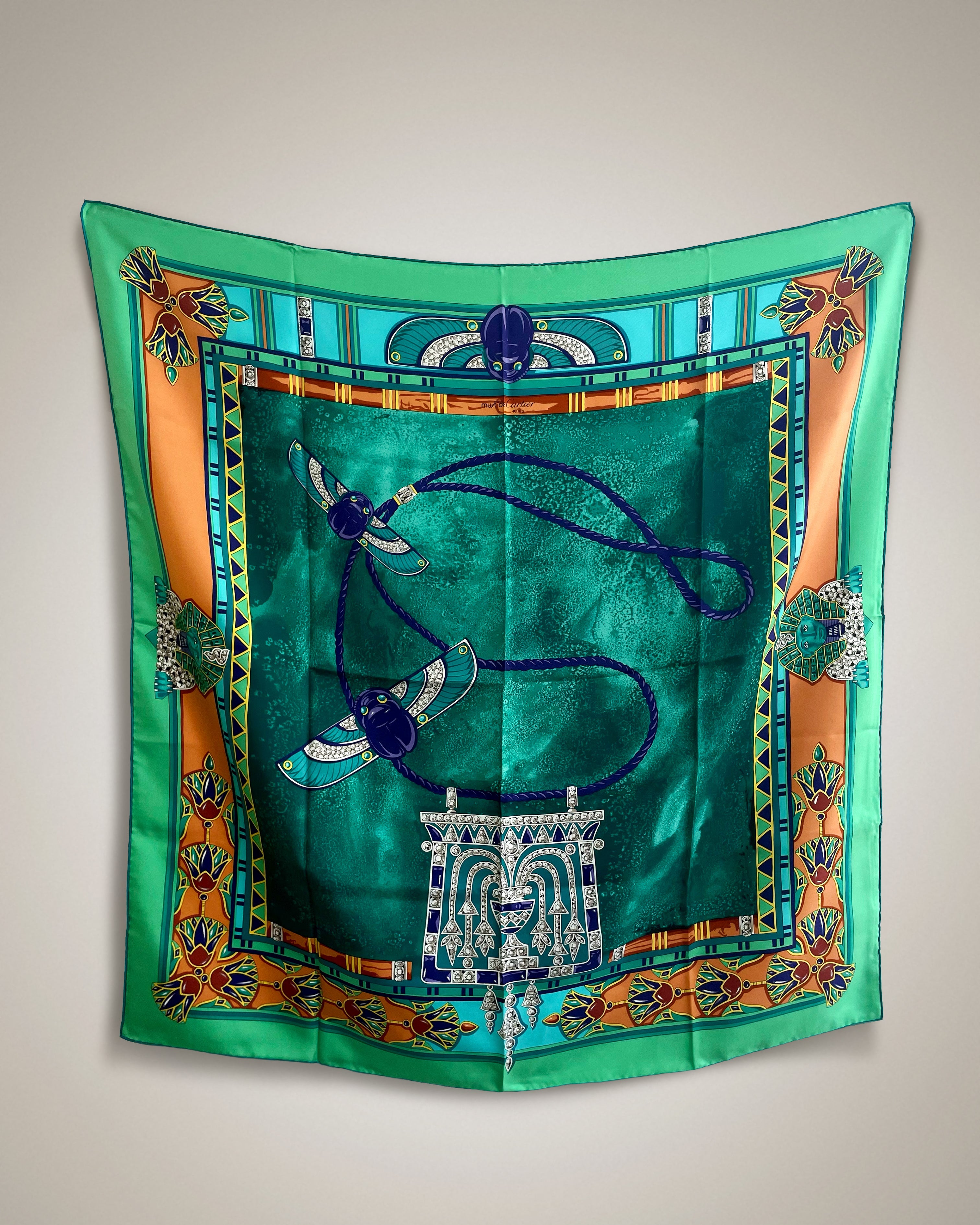 Vintage Must de Cartier Le Scarabée silk scarf in dark green featuring Egyptomania-inspired design, hanging display – Auric Vintage