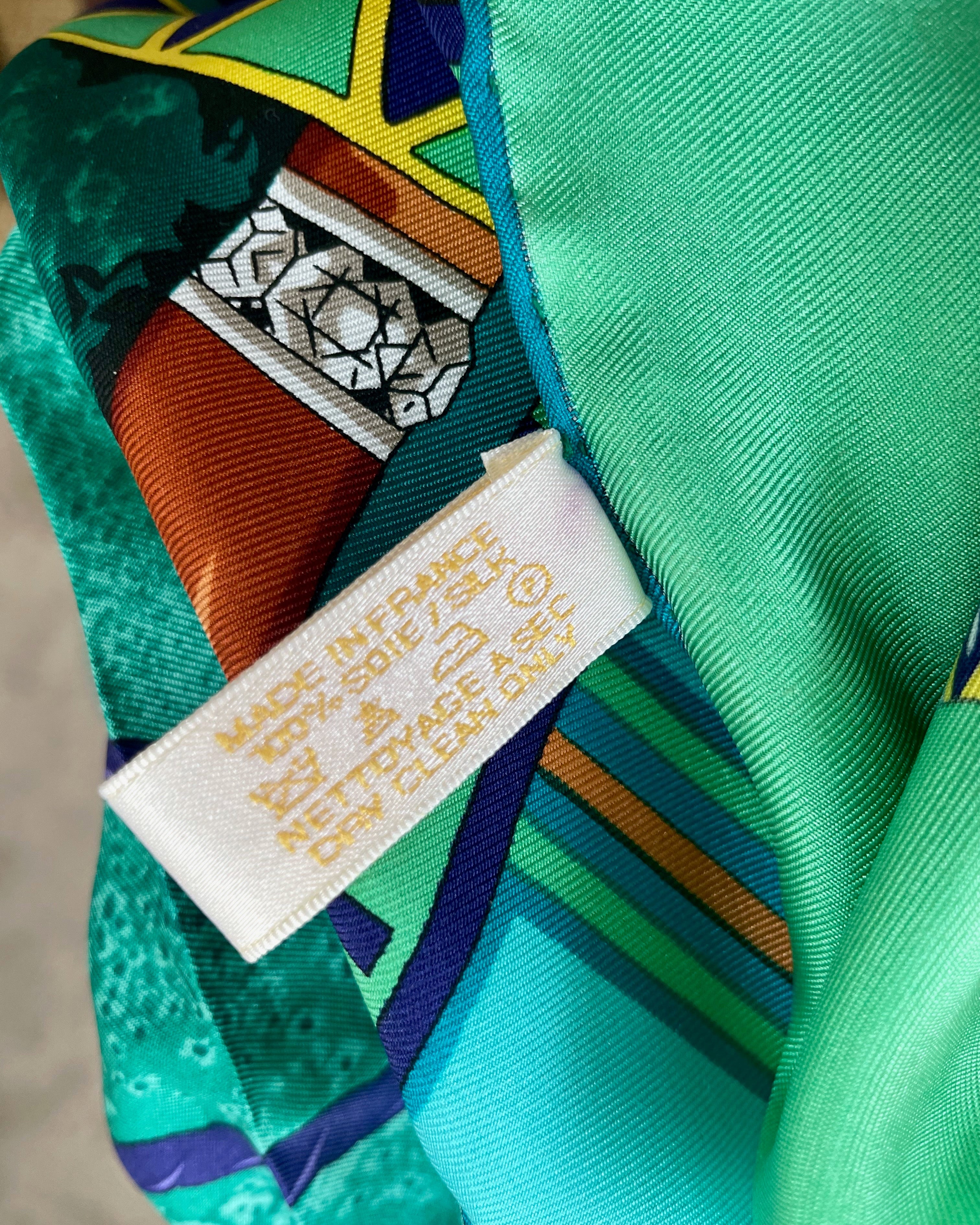 Close-up of original Must de Cartier tag back on vintage dark green Le Scarabée silk scarf – Auric Vintage