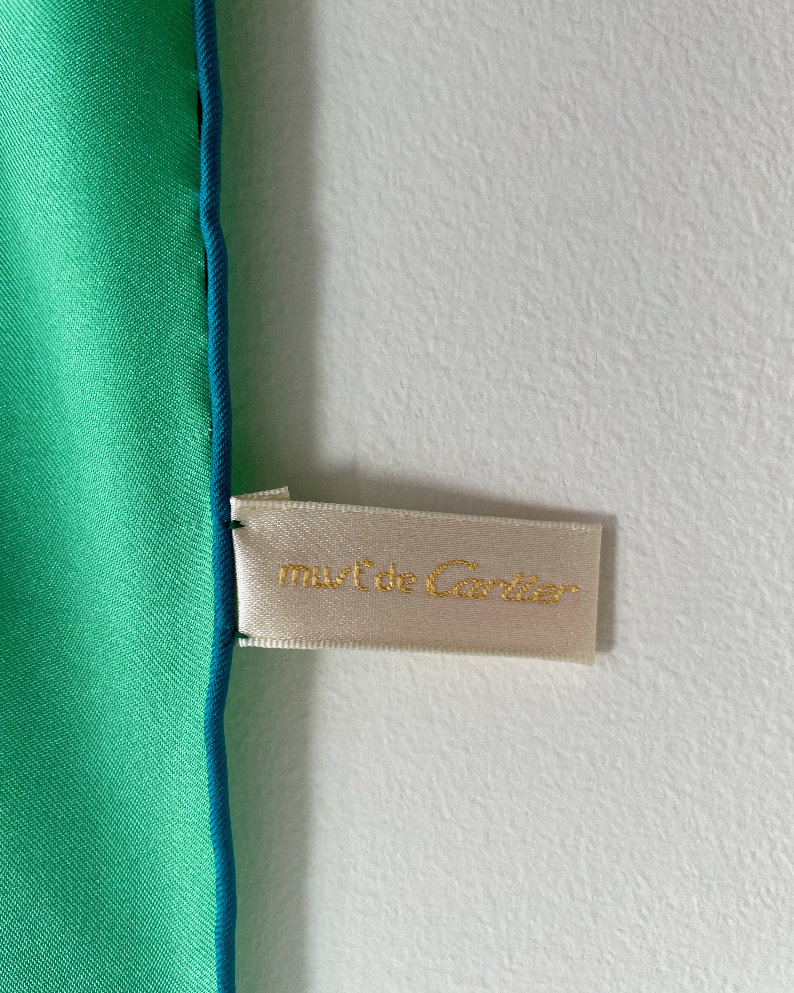 Close-up of original Must de Cartier tag front on vintage dark green Le Scarabée silk scarf – Auric Vintage