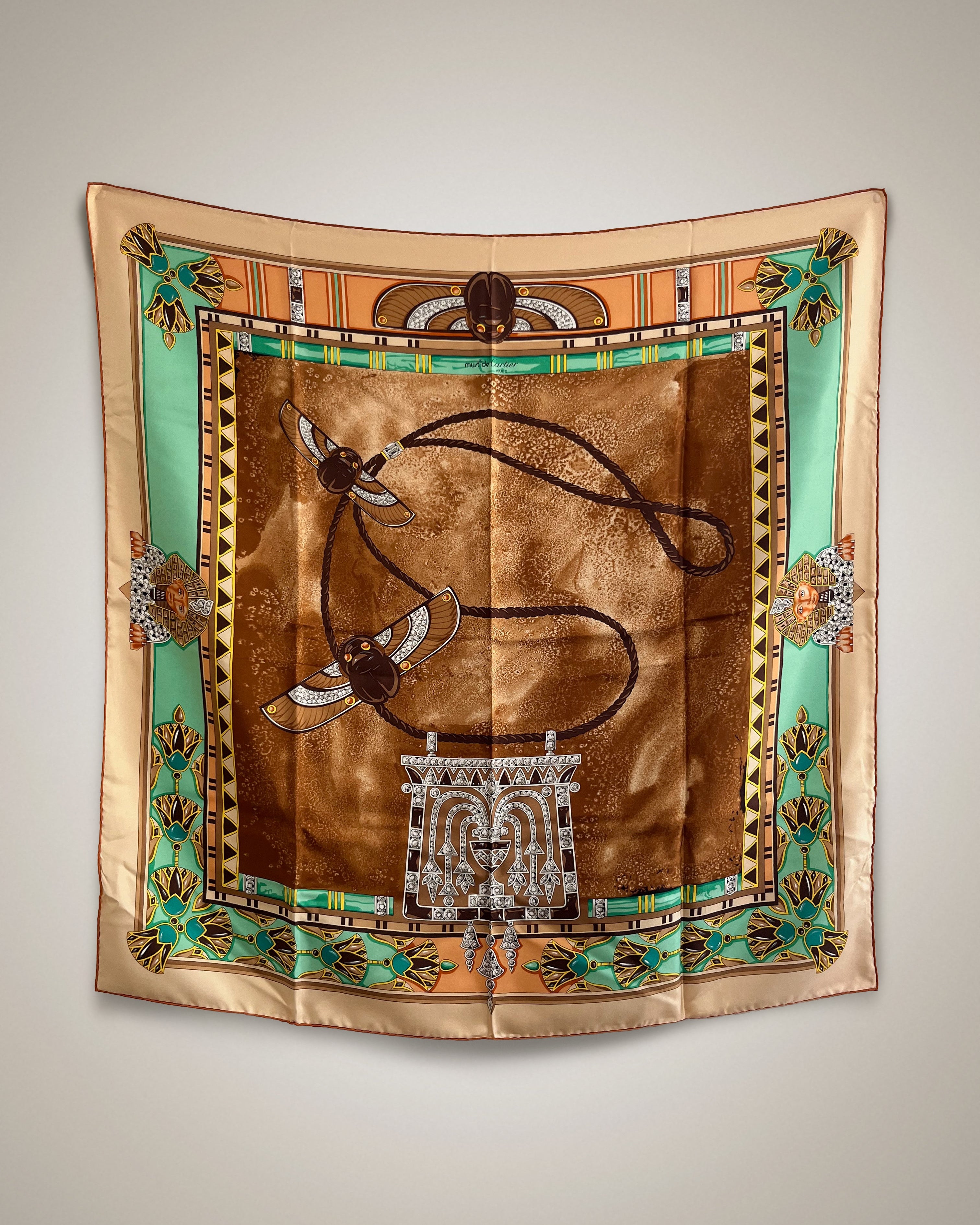 Vintage Must de Cartier Le Scarabée silk scarf in brown featuring Egyptomania-inspired design, hanging display – Auric Vintage