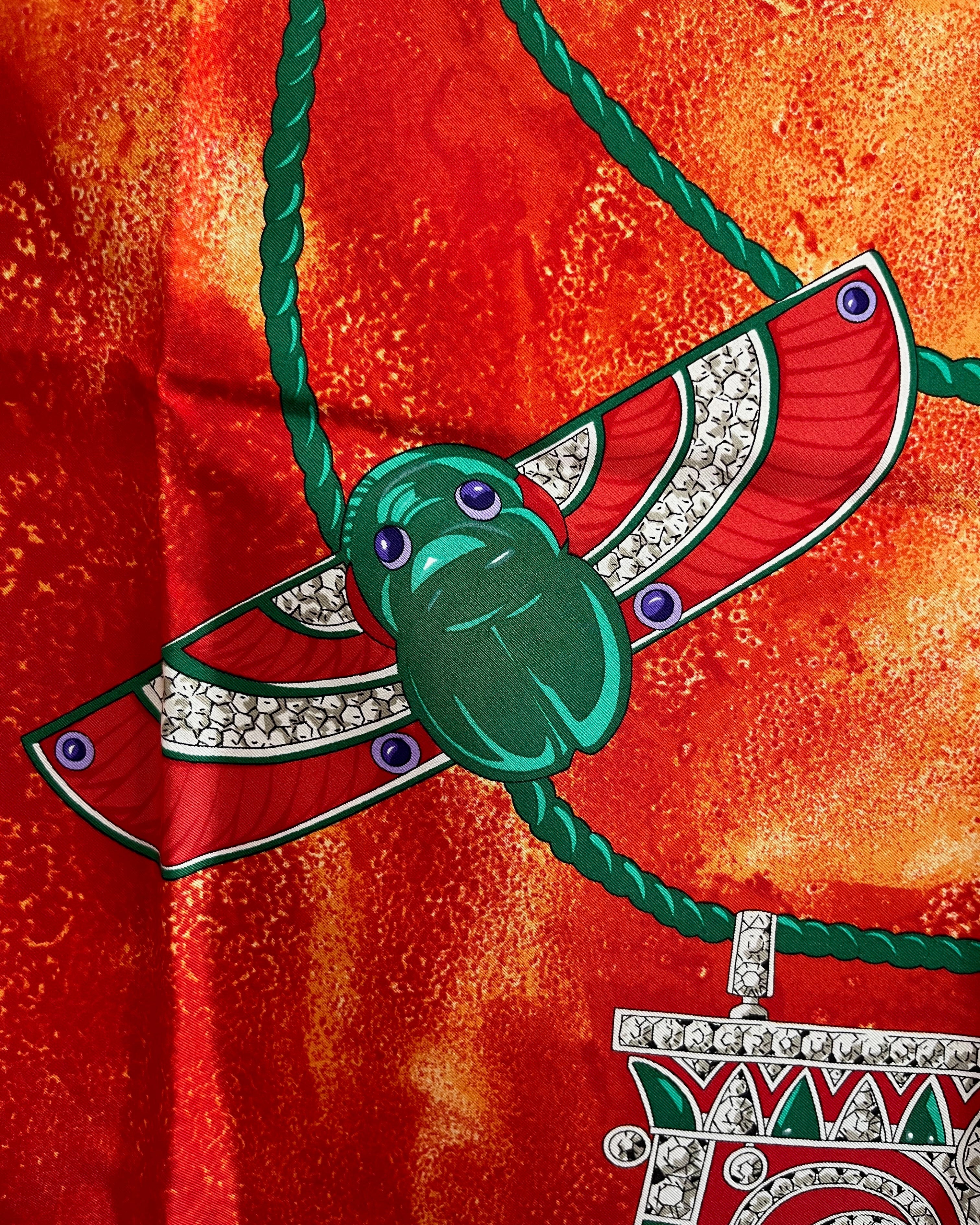 Close-up of central scarab motif on vintage red Must de Cartier Le Scarabée silk scarf – Auric Vintage