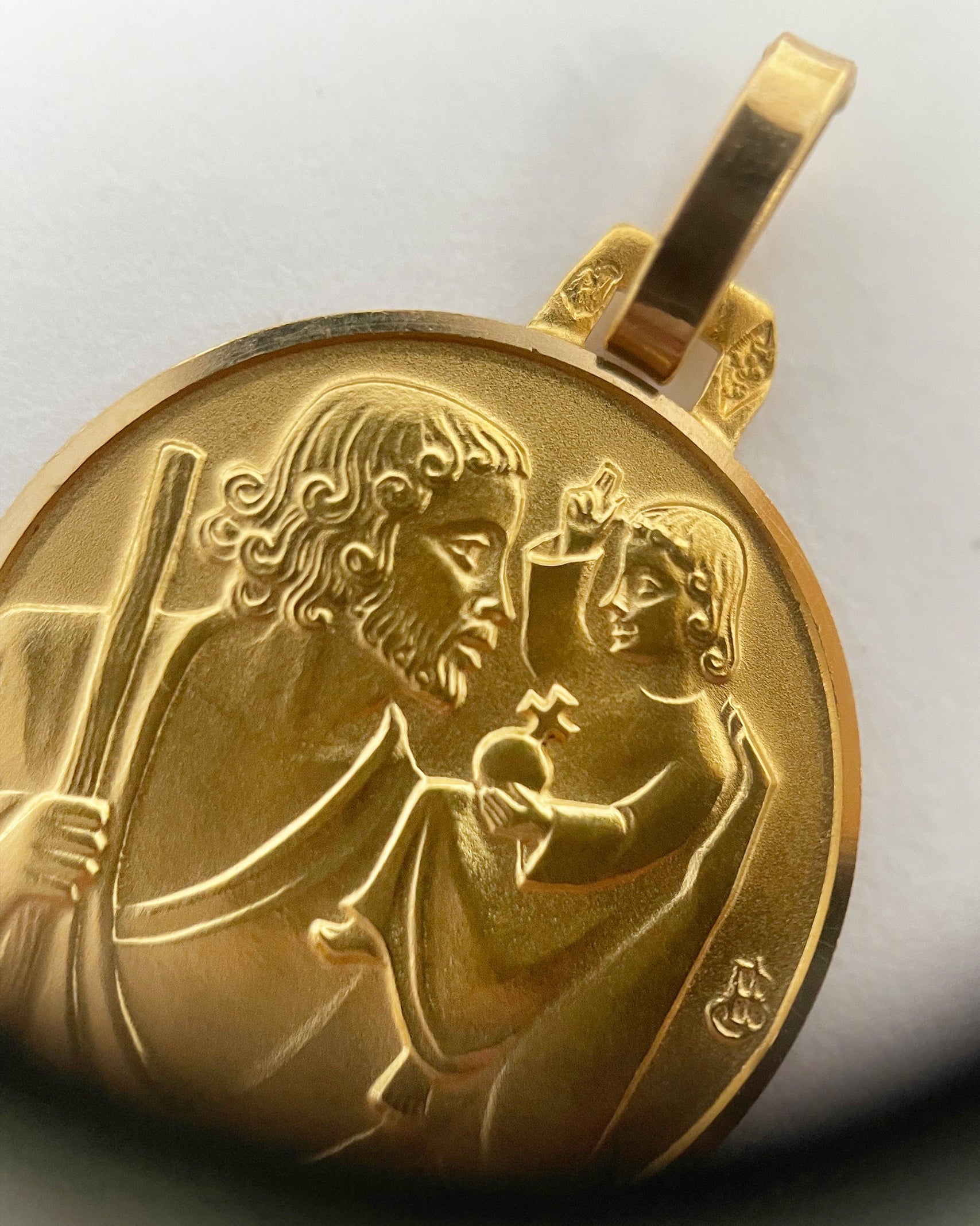 Close-up of vintage French 18kt gold St. Christopher medal through jeweller’s loupe showing detail – Auric Vintage
