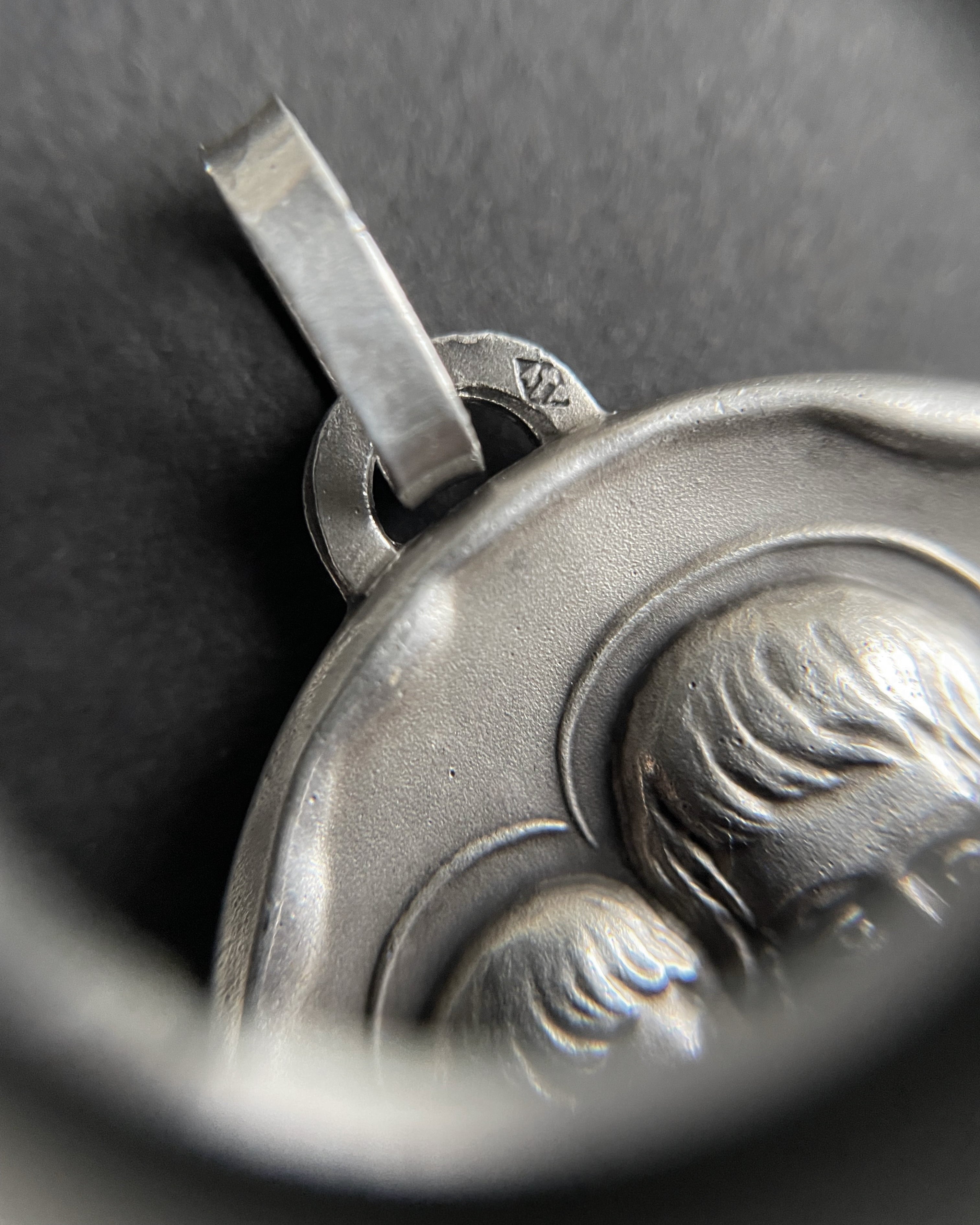 Close-up of 1970s French silver St. Christopher pendant through jeweller’s loupe showing makers markl – Auric Vintage