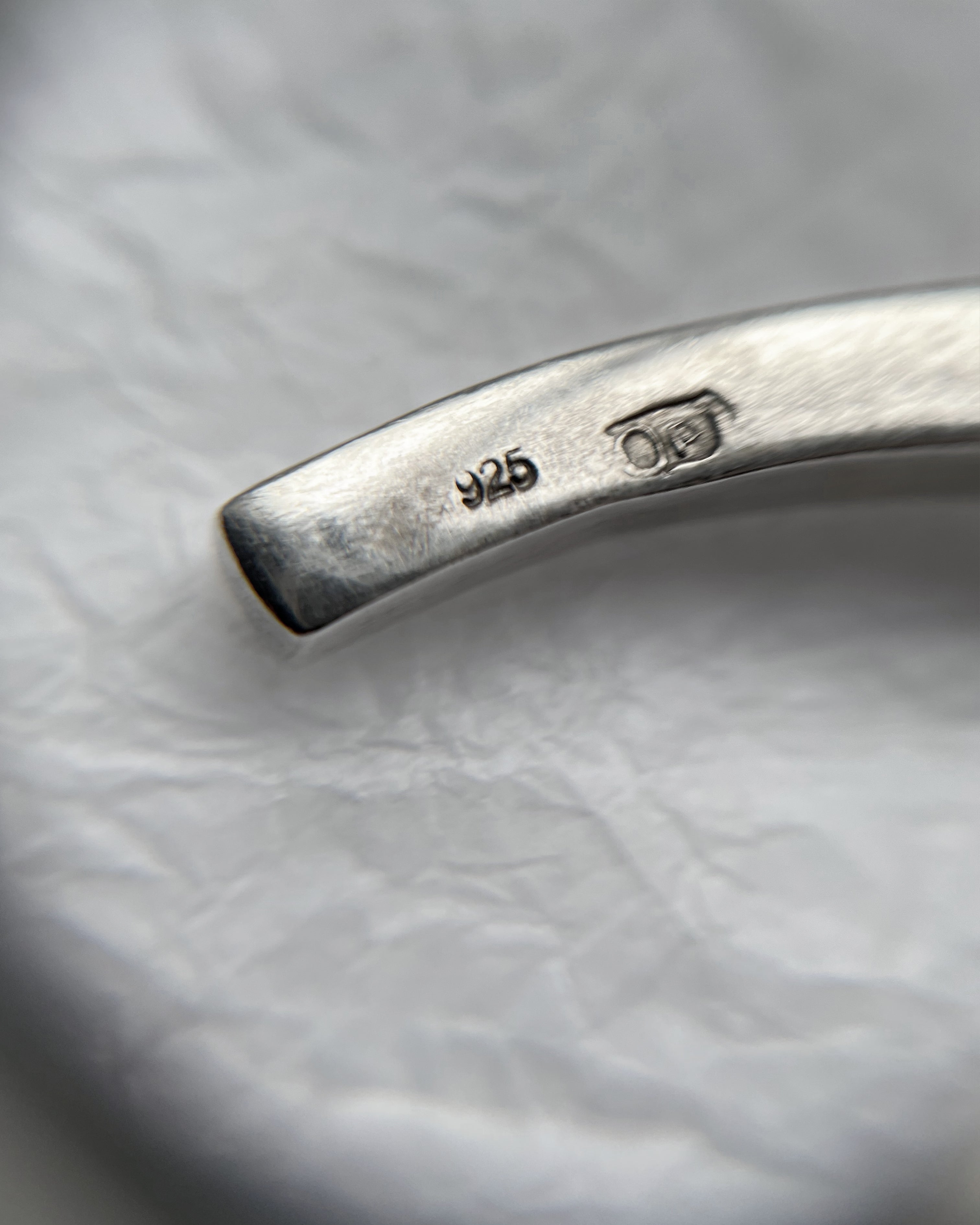 Close-up of 1990s sterling silver tri-torque bangle through jeweller’s loupe showing hallmark detail – Auric Vintage