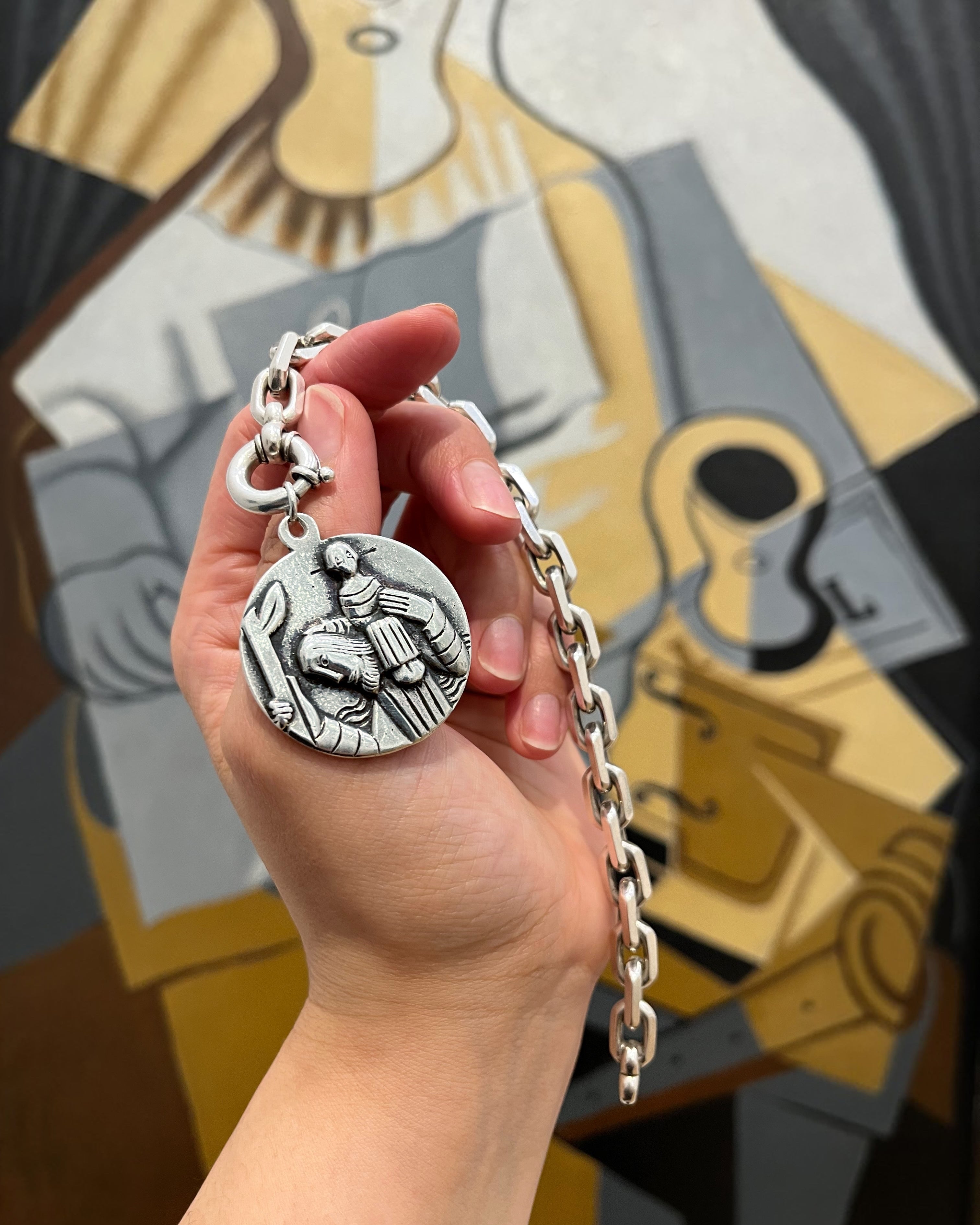 1970s sterling silver St. Christopher medallion held in hand on bracelet showing scale – Auric Vintage
