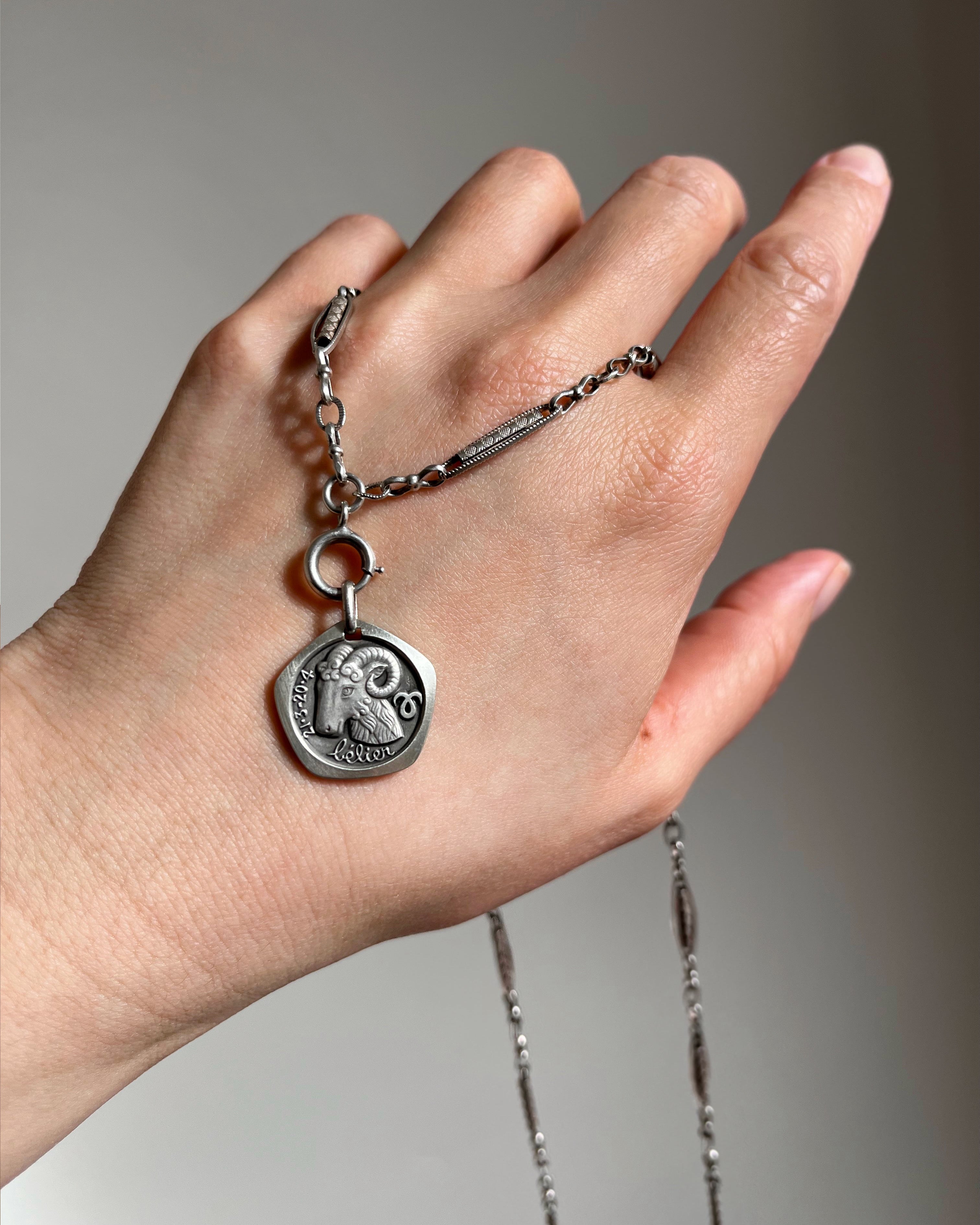 1970s French Aries zodiac pendant in 800 silver on chain draped over hand showing detail – Auric Vintage