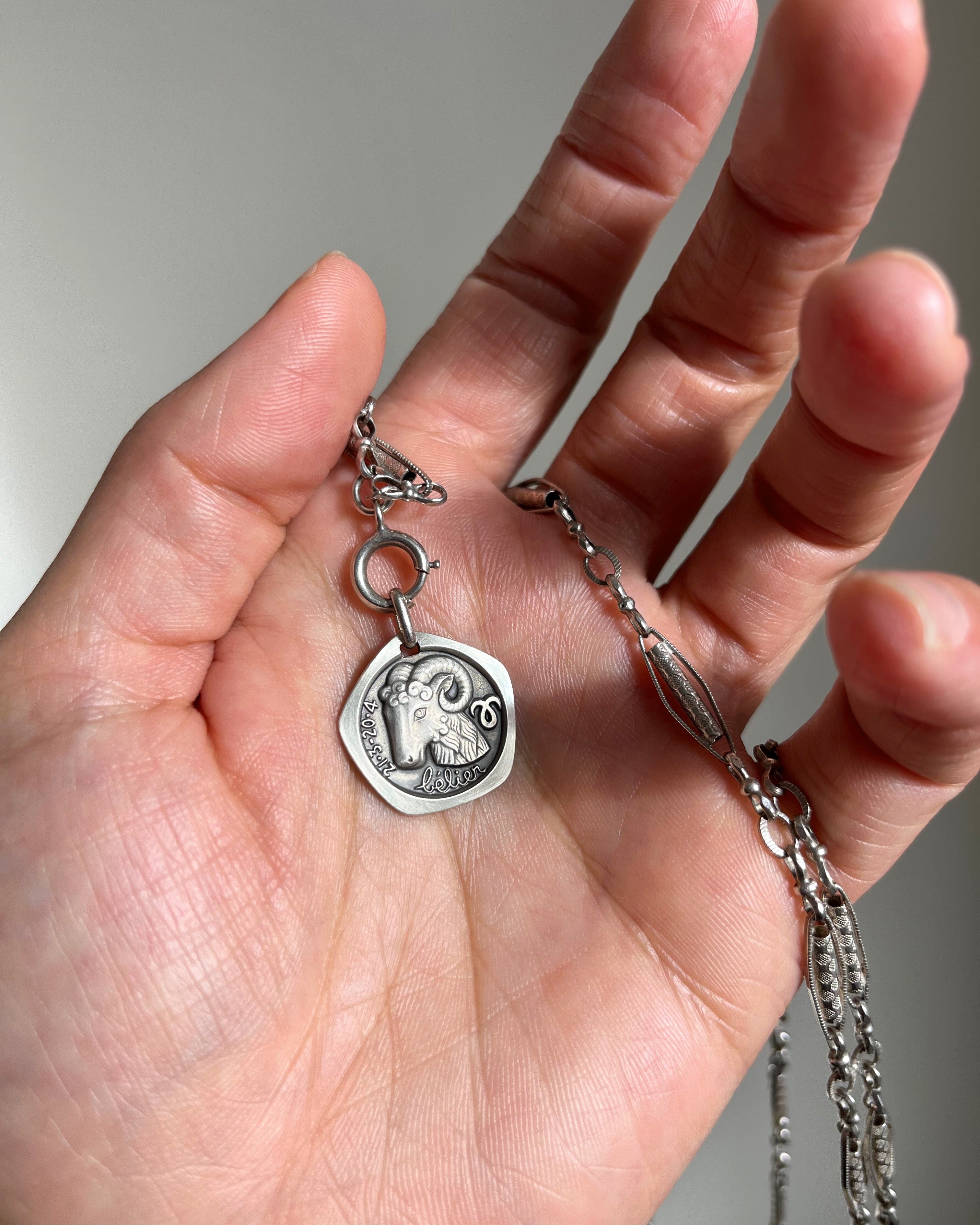 1970s French Aries zodiac pendant in 800 silver on chain held in palm showing scale – Auric Vintage