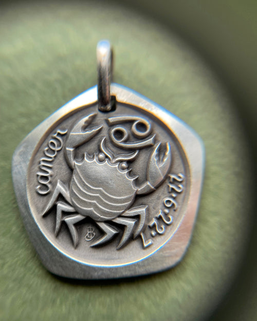 Close-up of 1970s French 800 silver Cancer zodiac pendant through jeweller’s loupe showing detail – Auric Vintage