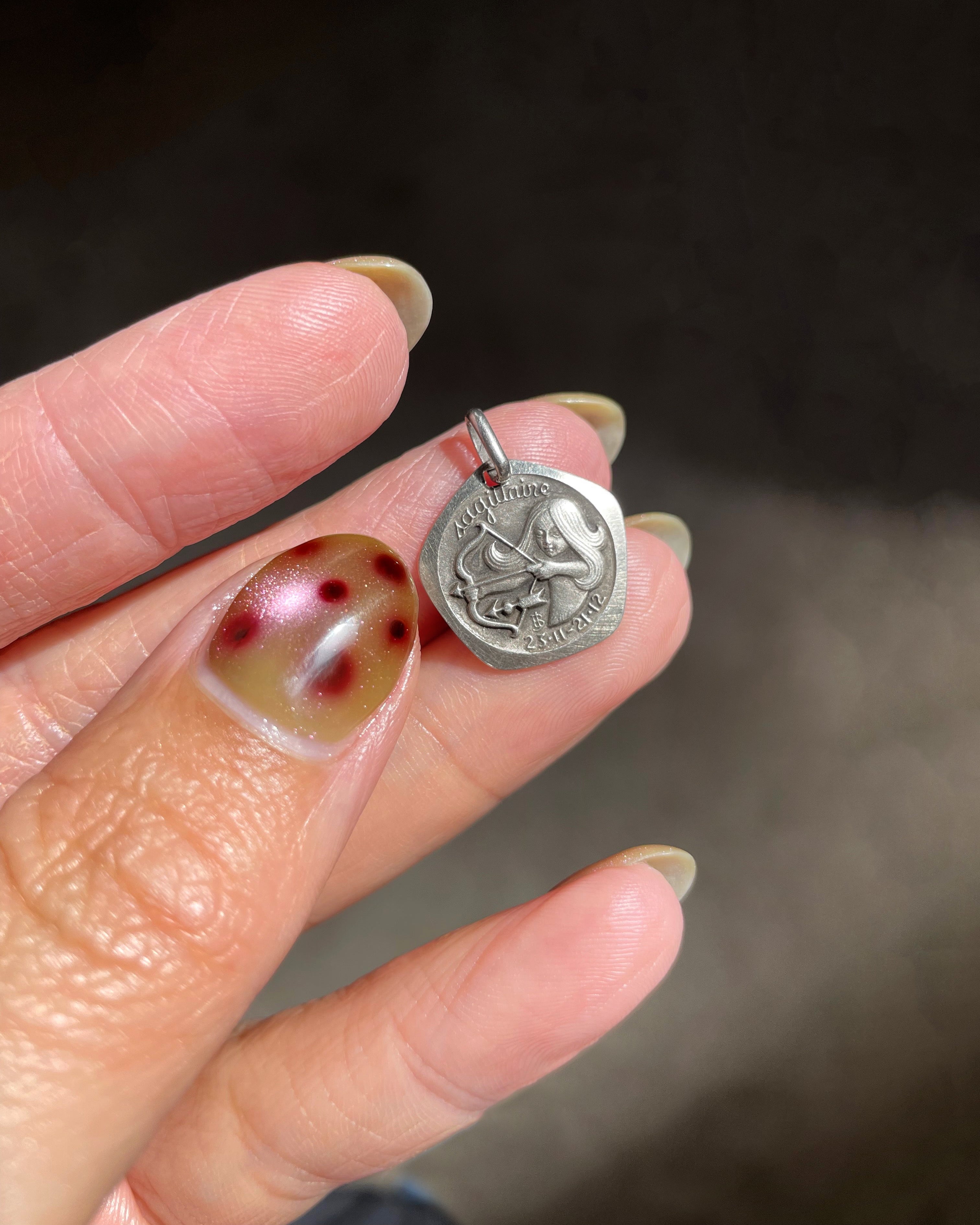 1970s French Sagittarius zodiac mini pendant in 800 silver with female archer design by Jean Balme held in hand showing scale – Auric Vintage